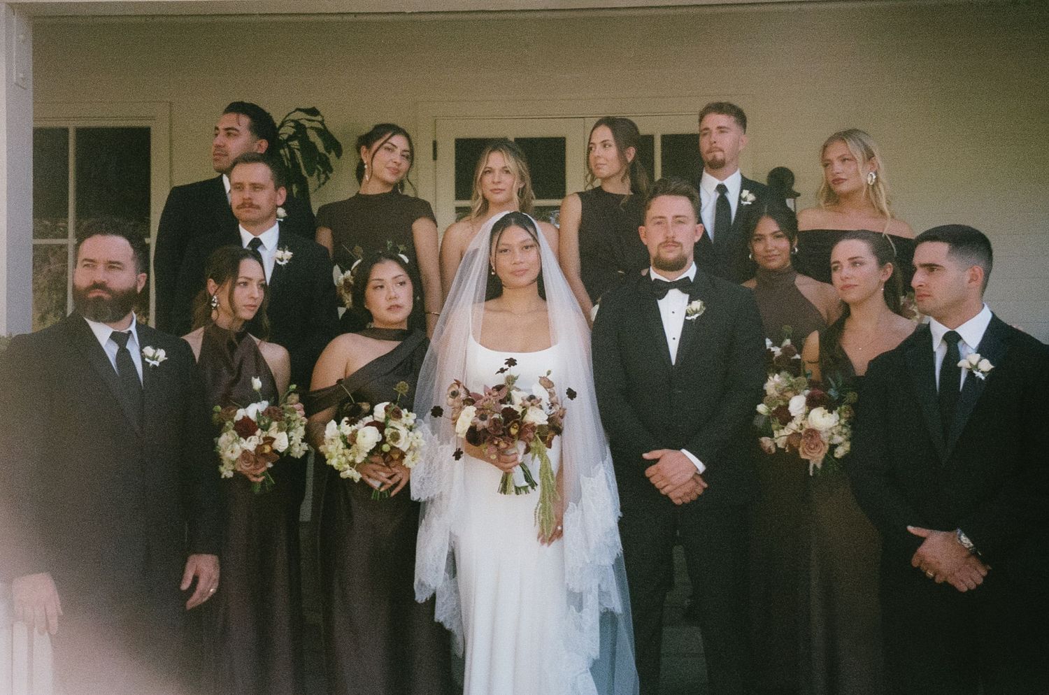 Wedding party gathered indoors wearing formal black and white attire.