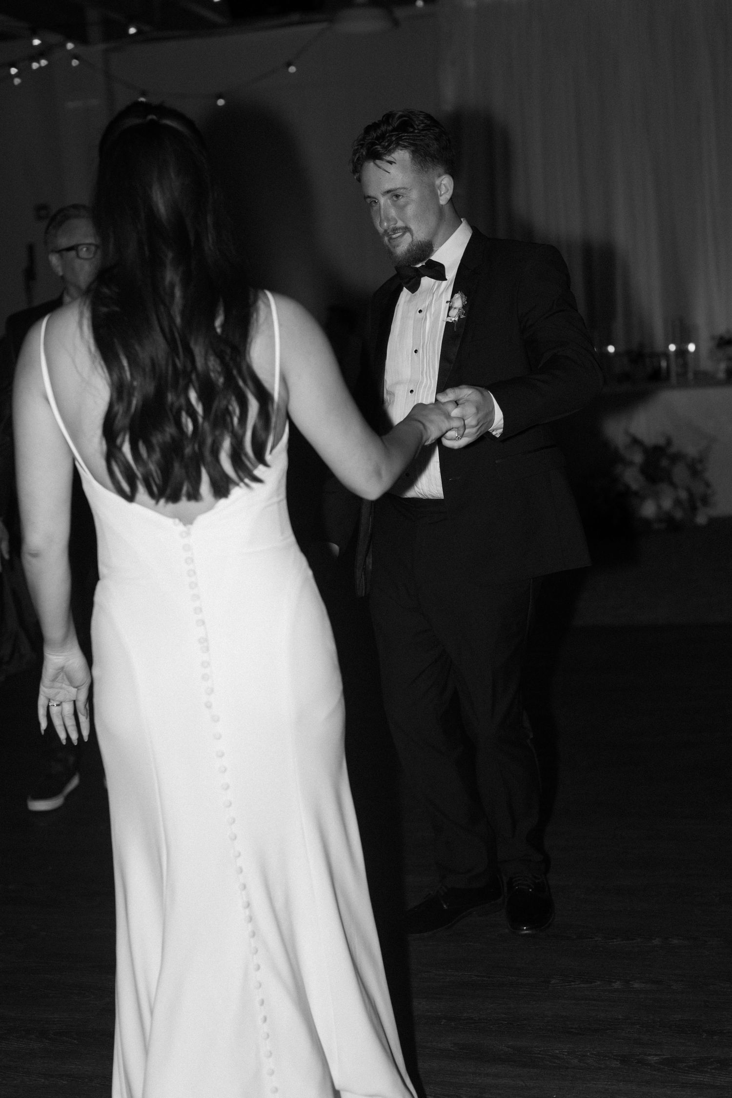 Back view of bride in white dress with button details during evening reception.