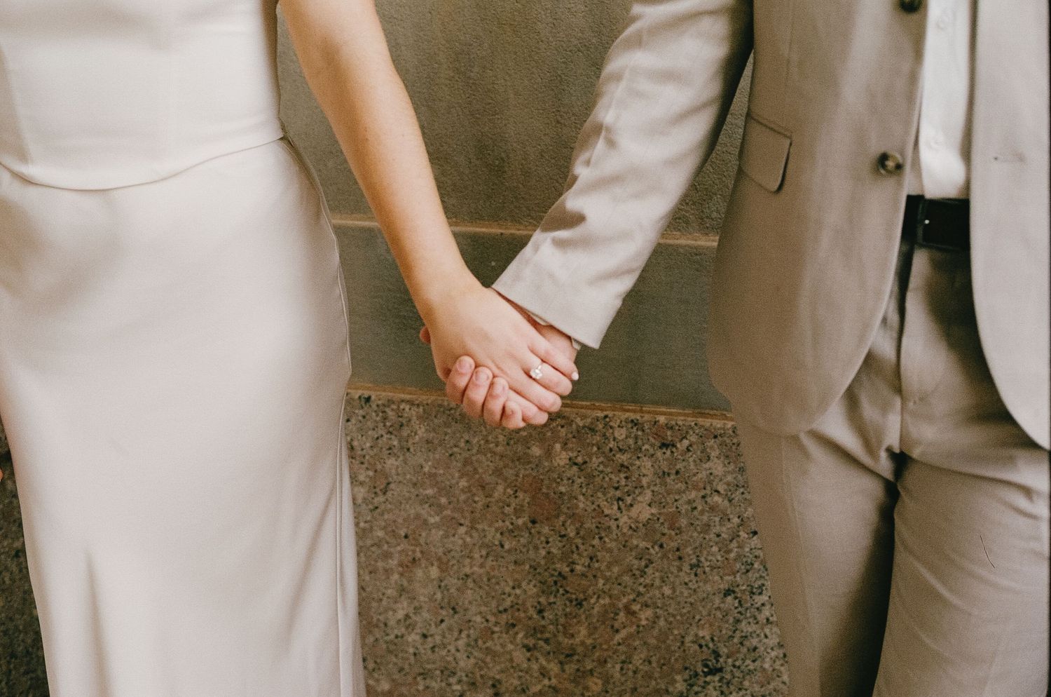Close-up view of a couple in coordinated neutral outfits standing together.