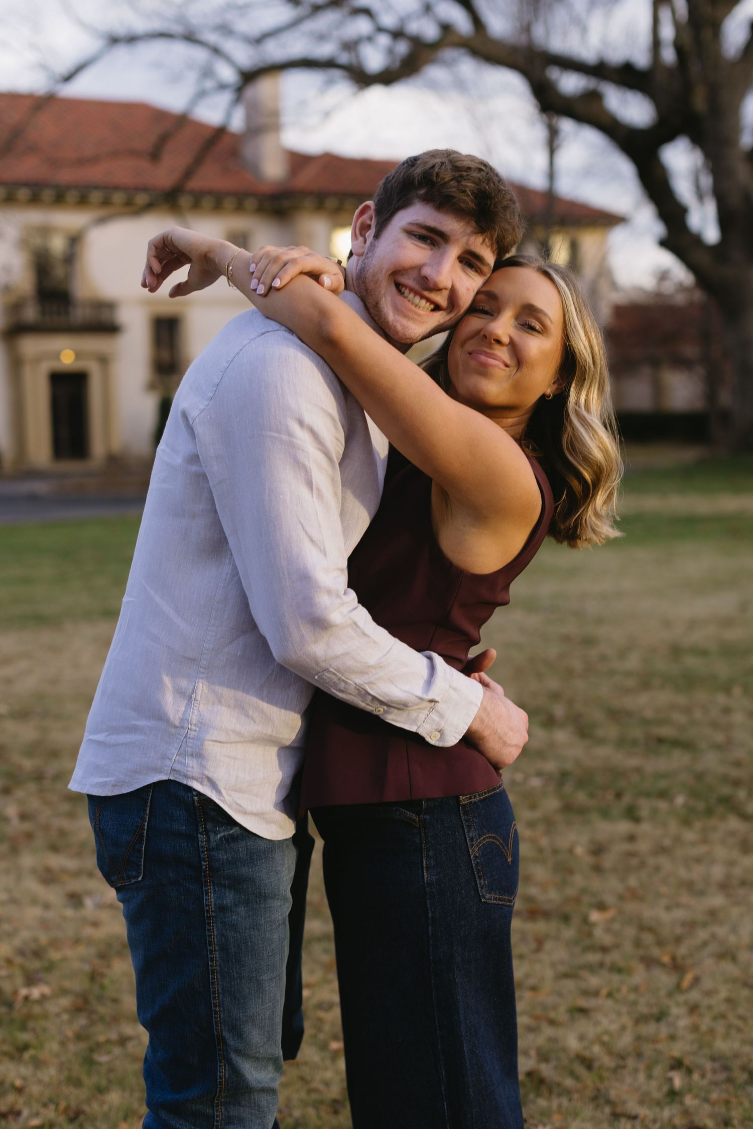 Couple dancing and laughing together in a grassy field.