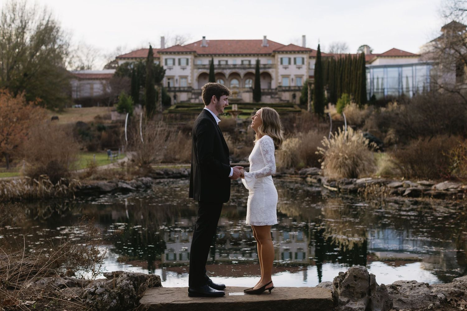 A romantic winter scene by a pond with formal attire and natural landscaping.