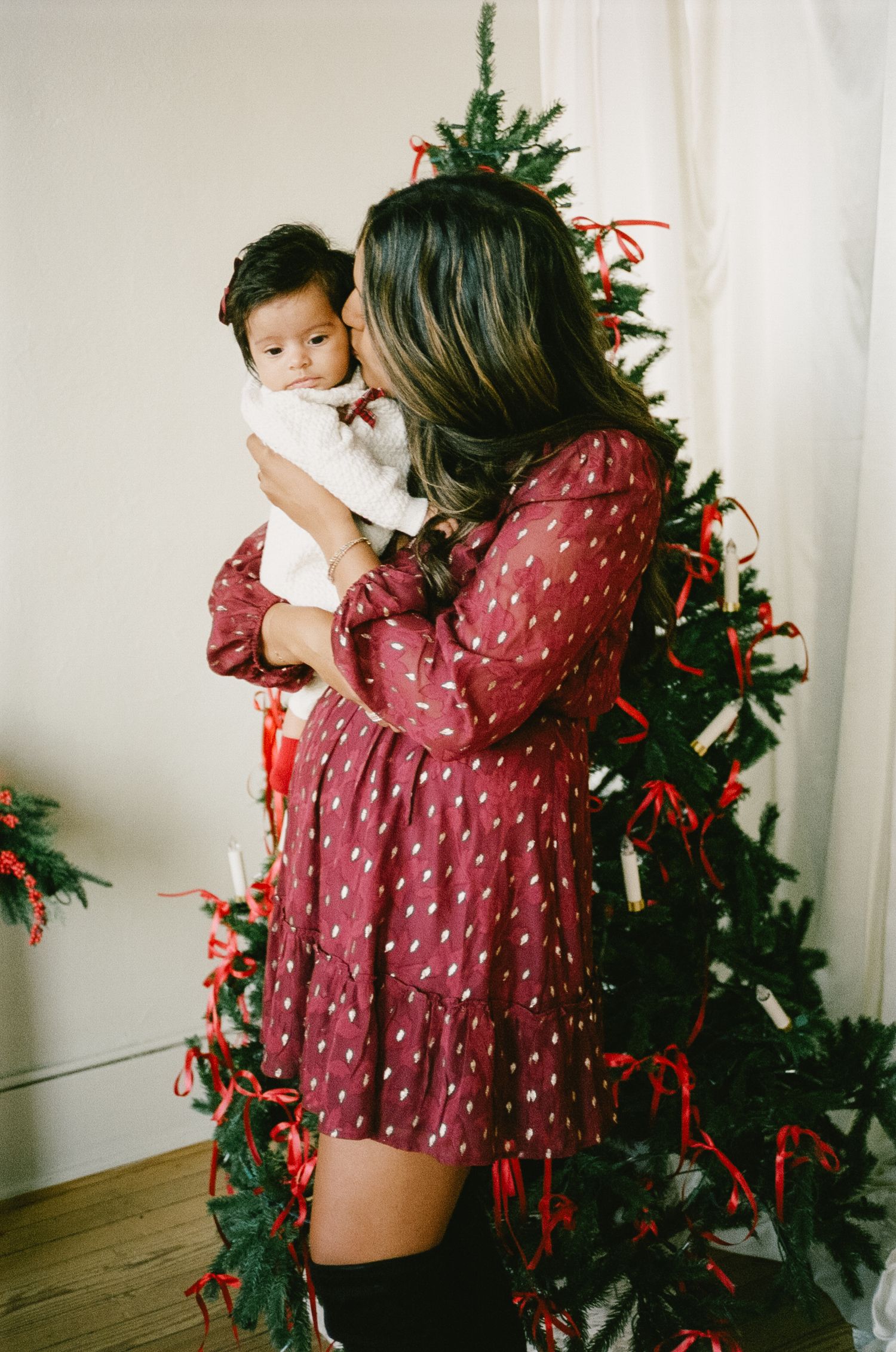 A polka dot dress and Christmas decor create a festive holiday scene with red ribbons and greenery.
