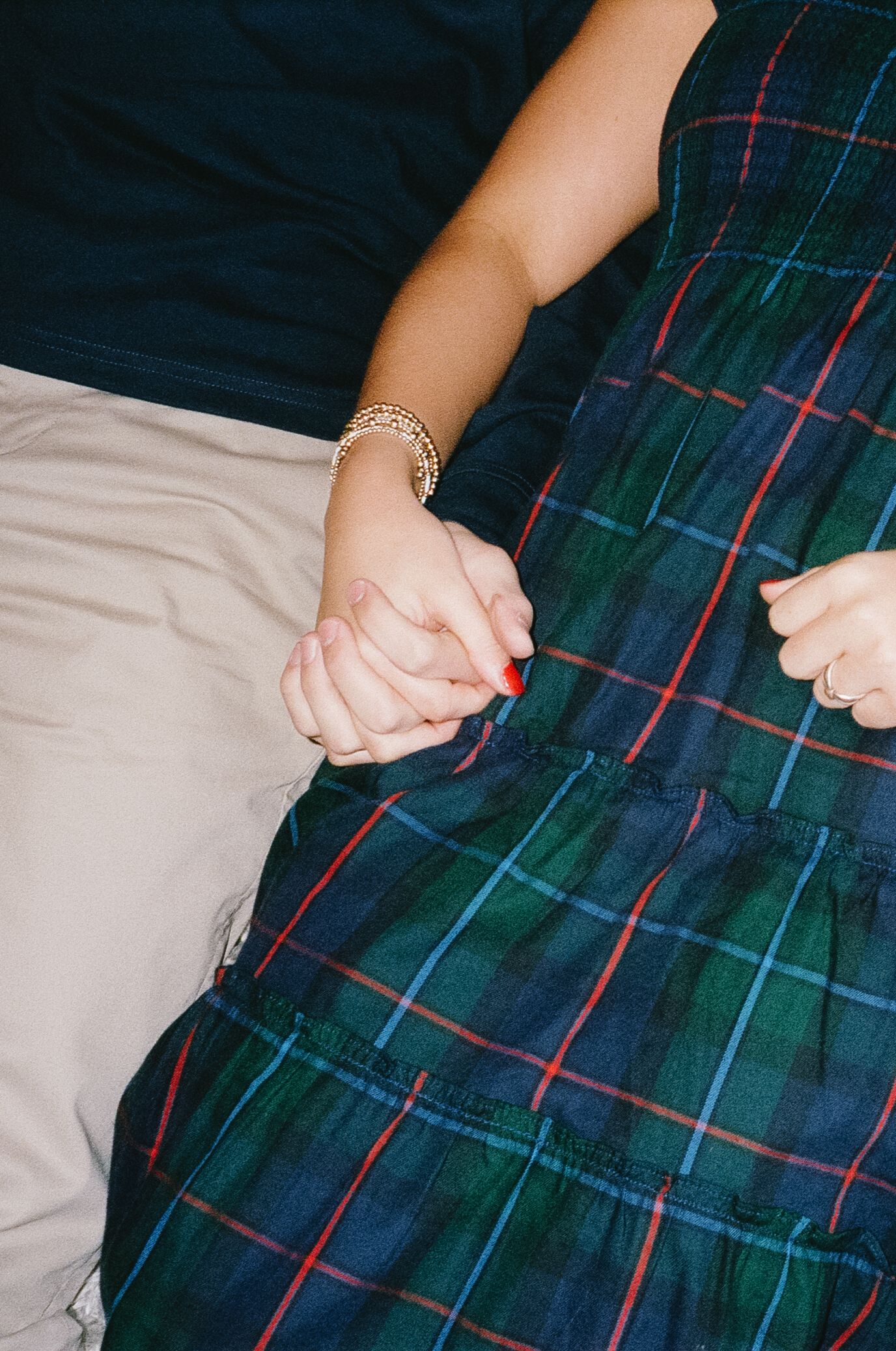 Close-up view of hands holding plaid fabric and khaki material showing texture and pattern details.