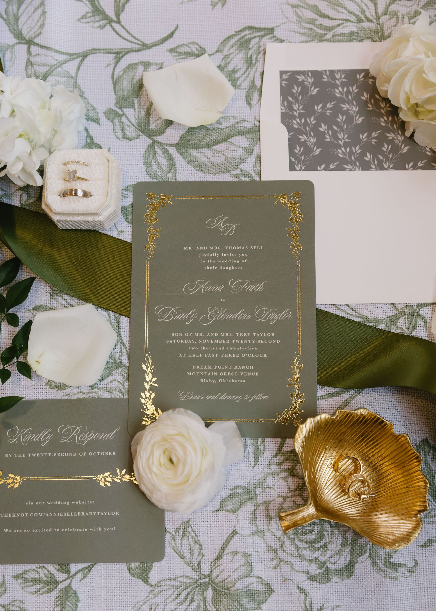 Elegant sage green wedding invitations with gold foil details and white floral accents.