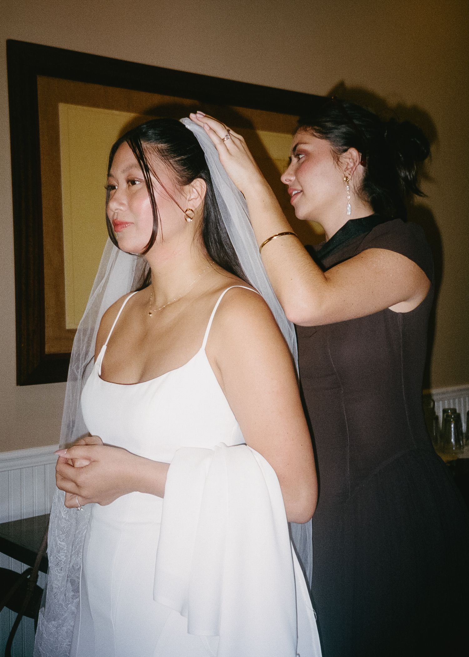 Wedding preparations scene showing a white dress being adjusted in a dimly lit room.