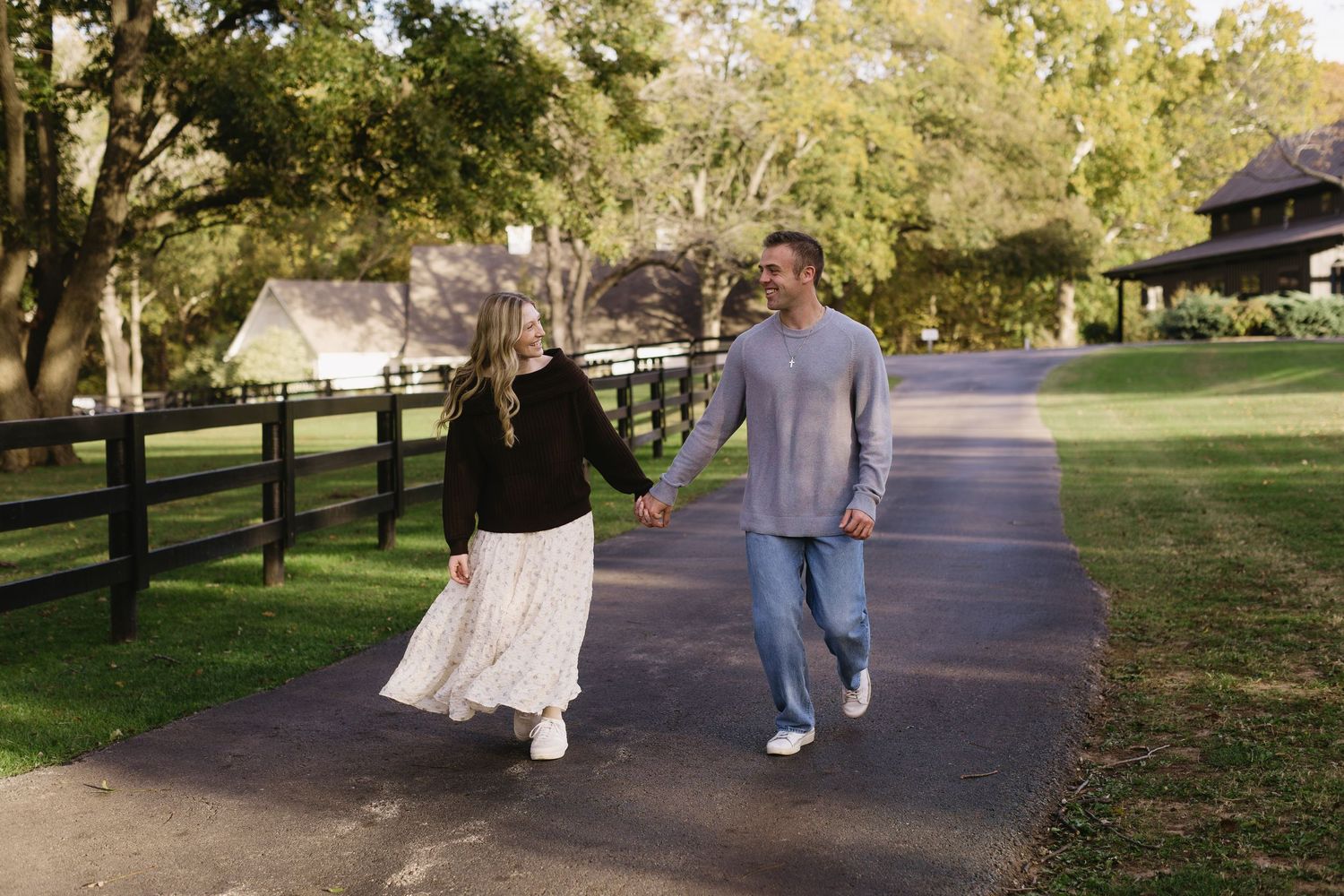 A couple shares a romantic moment while walking on a tree-lined path during autumn.
