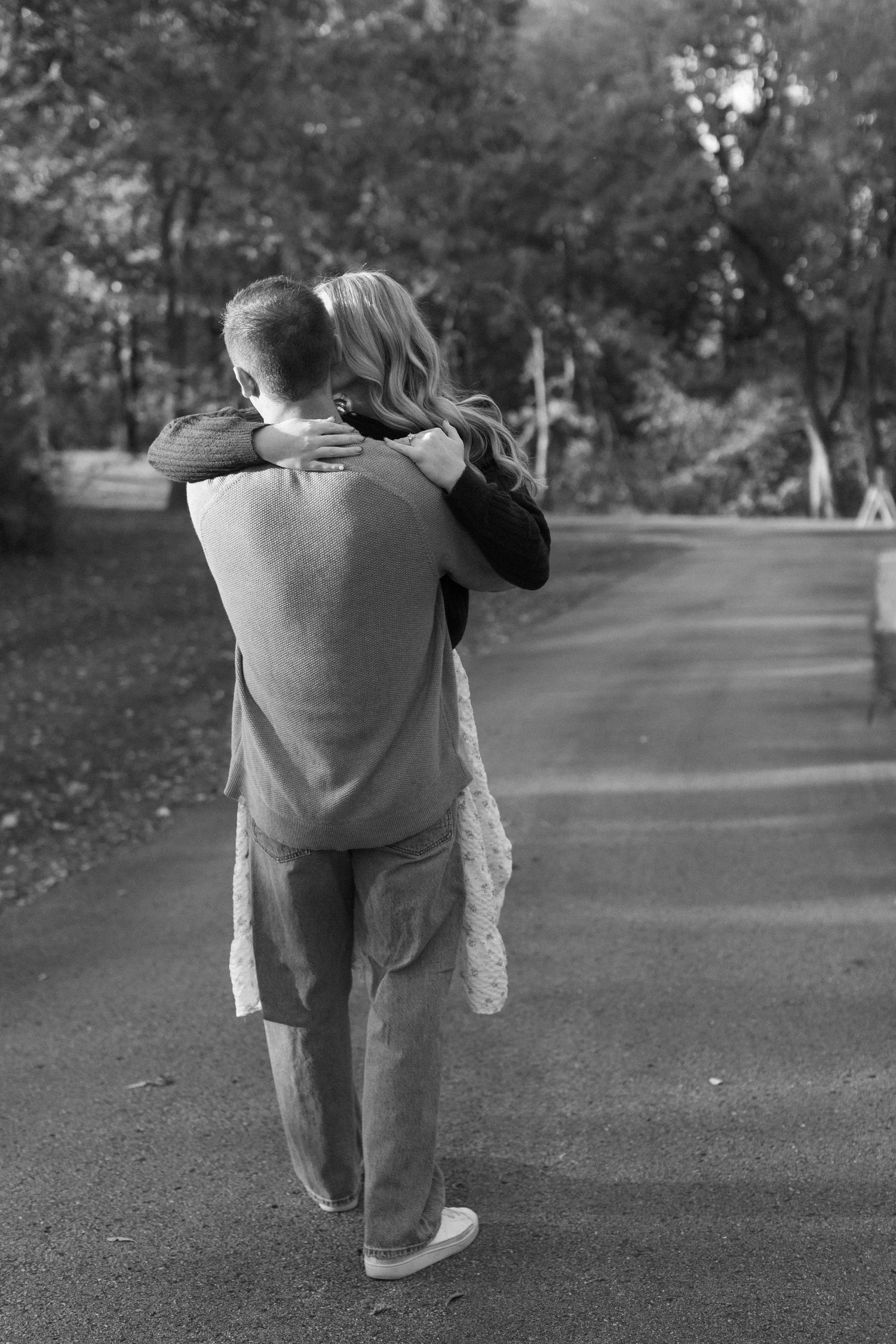 A romantic black and white photo sequence shows a couple embracing and spinning together on a tree-lined path.