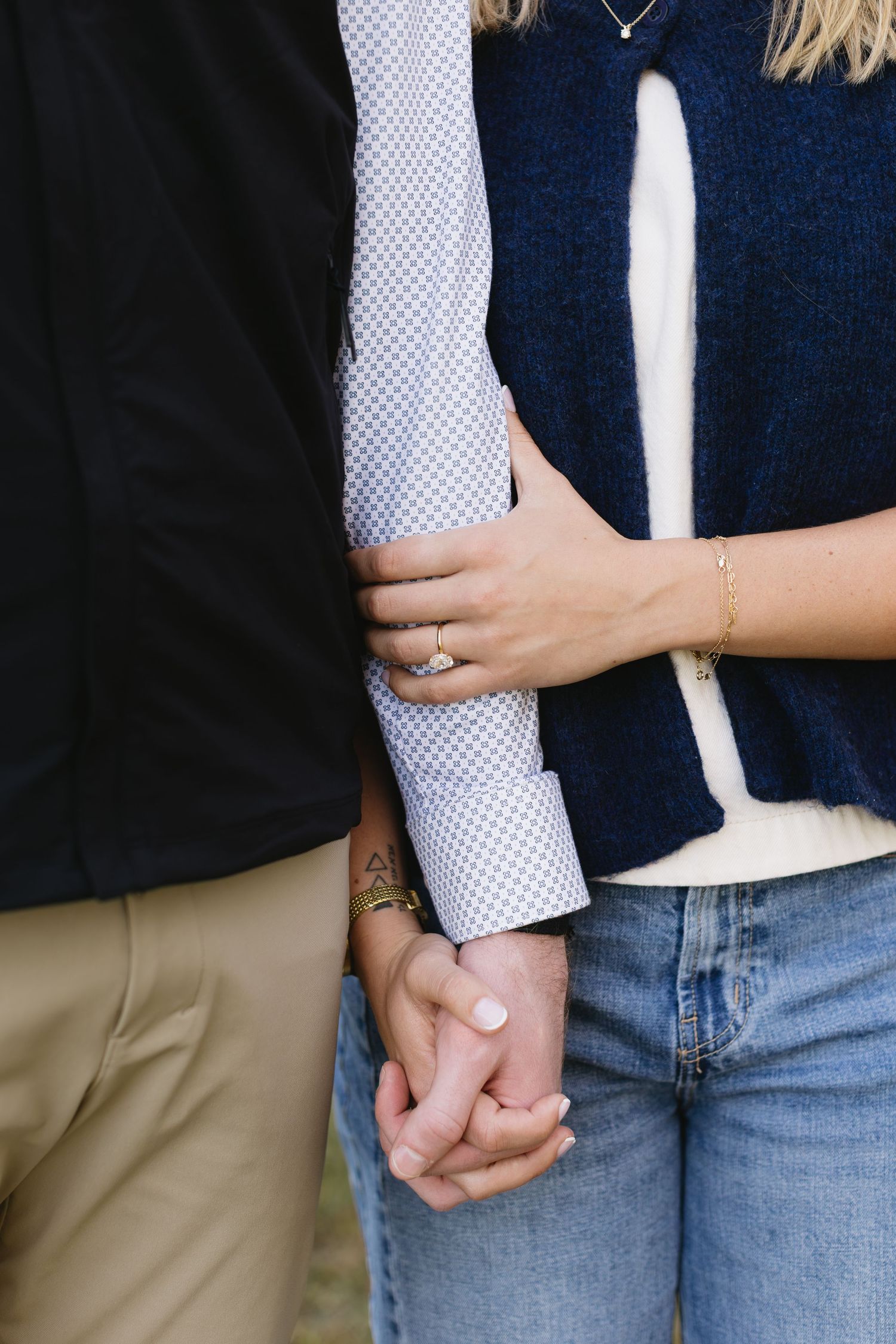Close-up of two people holding hands wearing contrasting casual outfits.