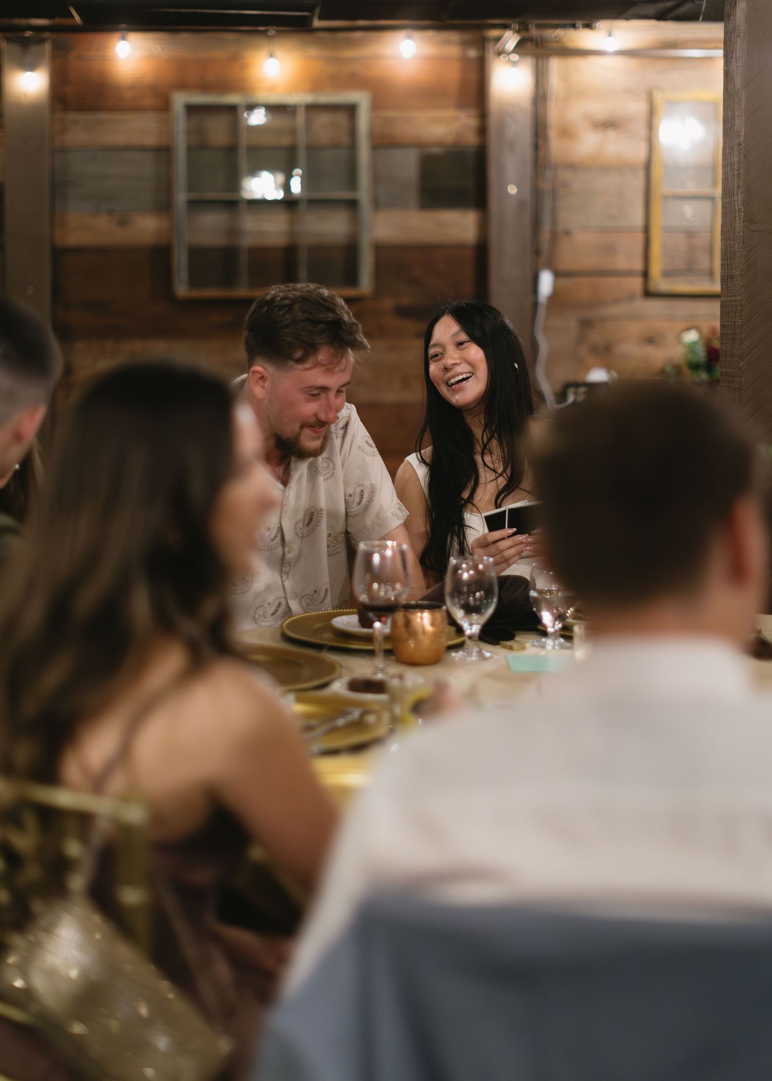 Guests enjoying a warm dinner gathering in a rustic wooden interior with ambient lighting.
