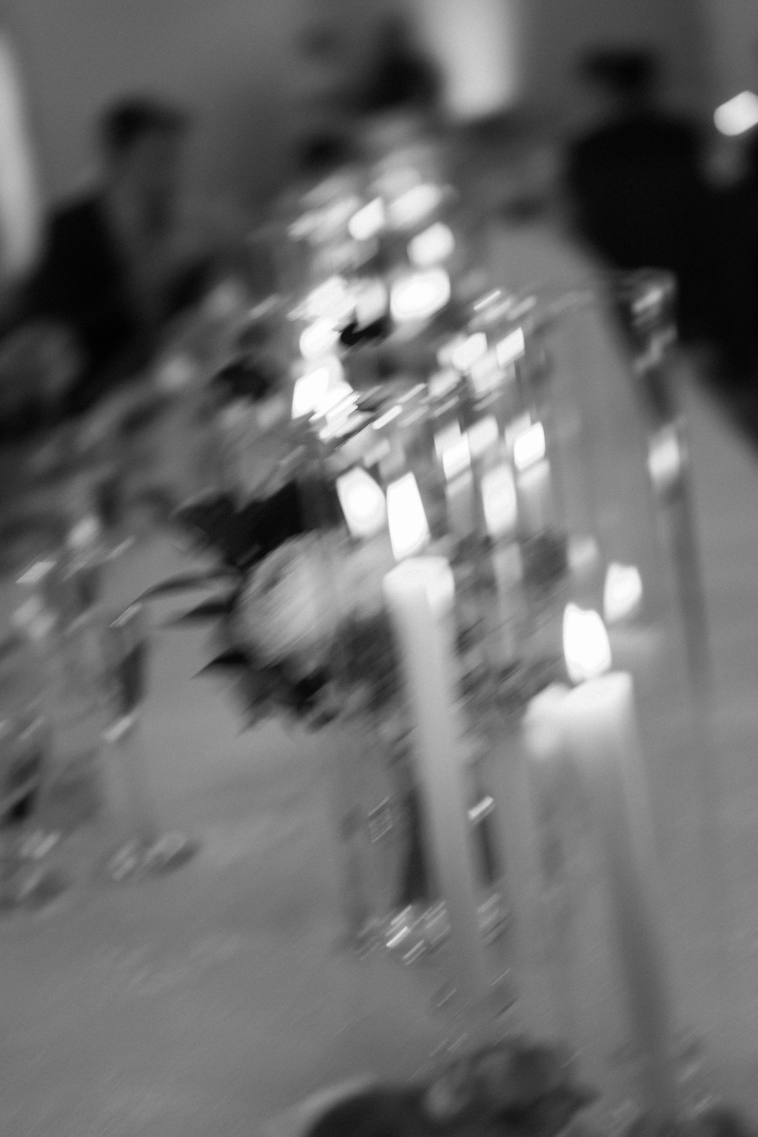 Abstract blurred image of candlelit wedding reception decor in black and white.