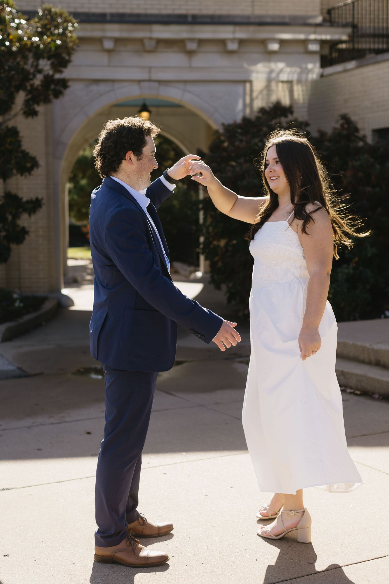 Playful dance sequence of couple in white dress and navy suit on sunny patio.