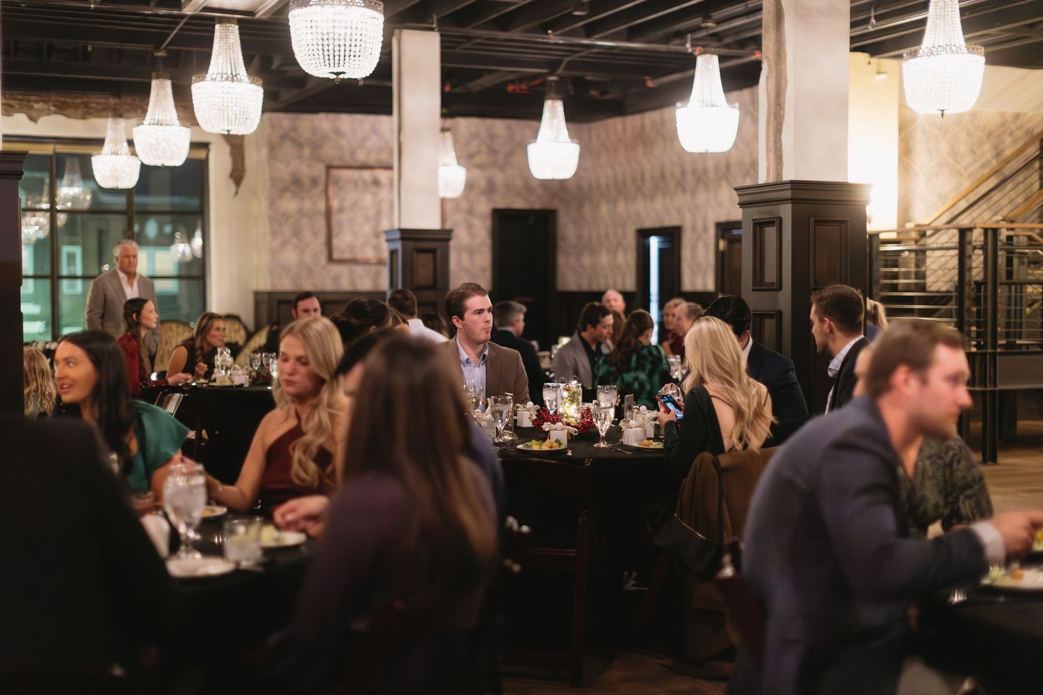 Elegant evening event space with exposed brick walls and multiple hanging light fixtures.