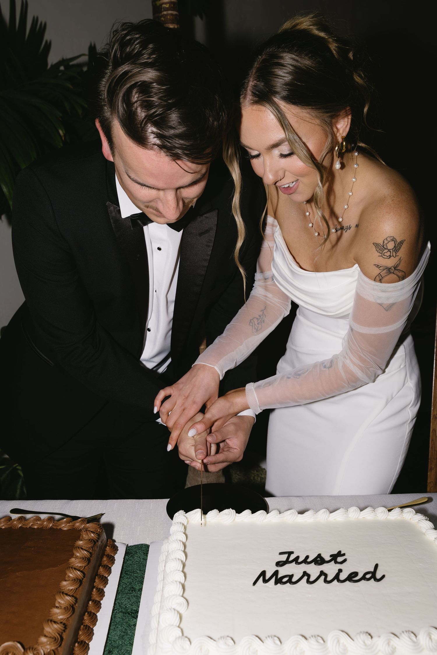 Wedding cake cutting moment with a classic white cake decorated with 'Just Married' text.