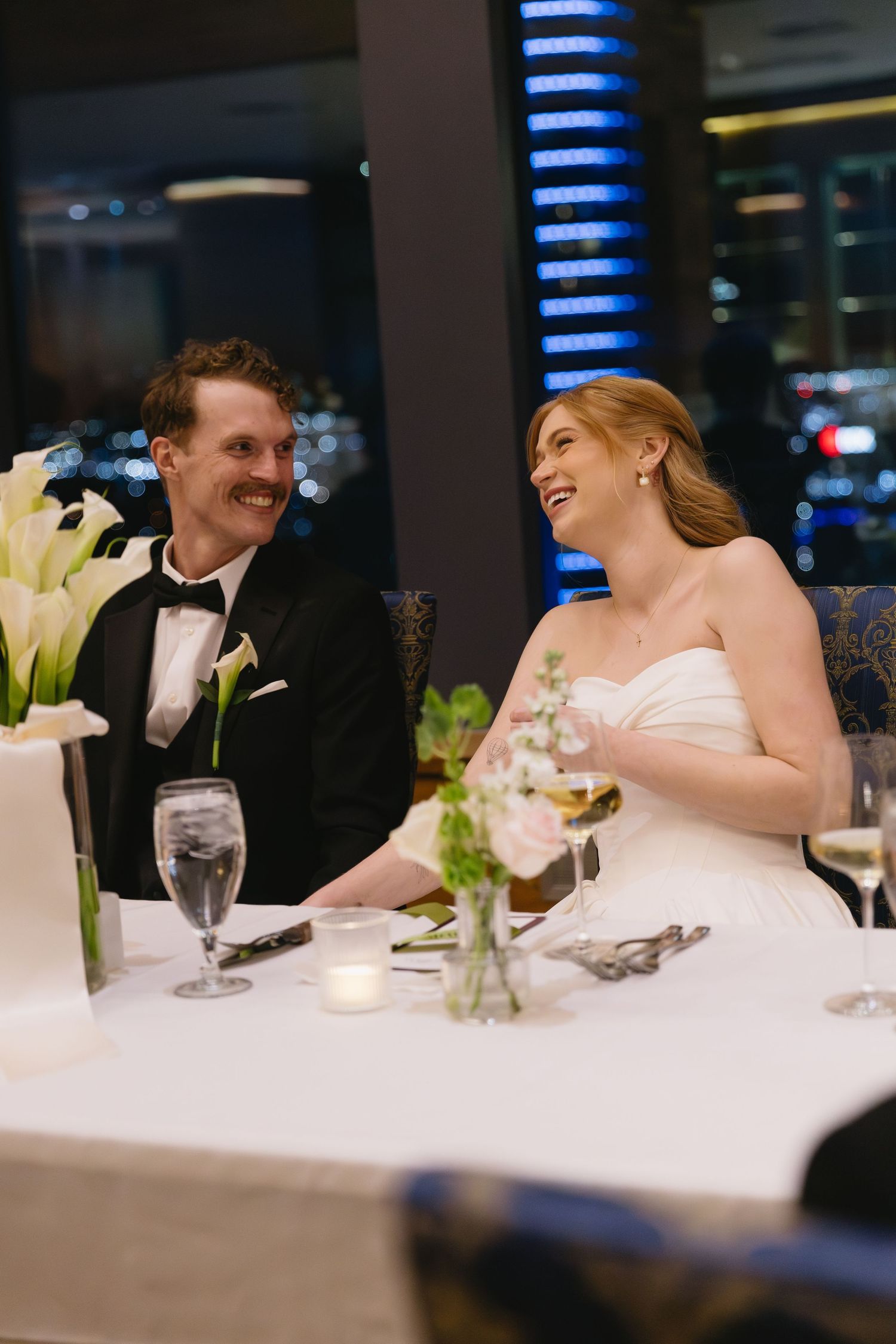 Elegant wedding dinner table setting with white flowers and couple sharing intimate moments.