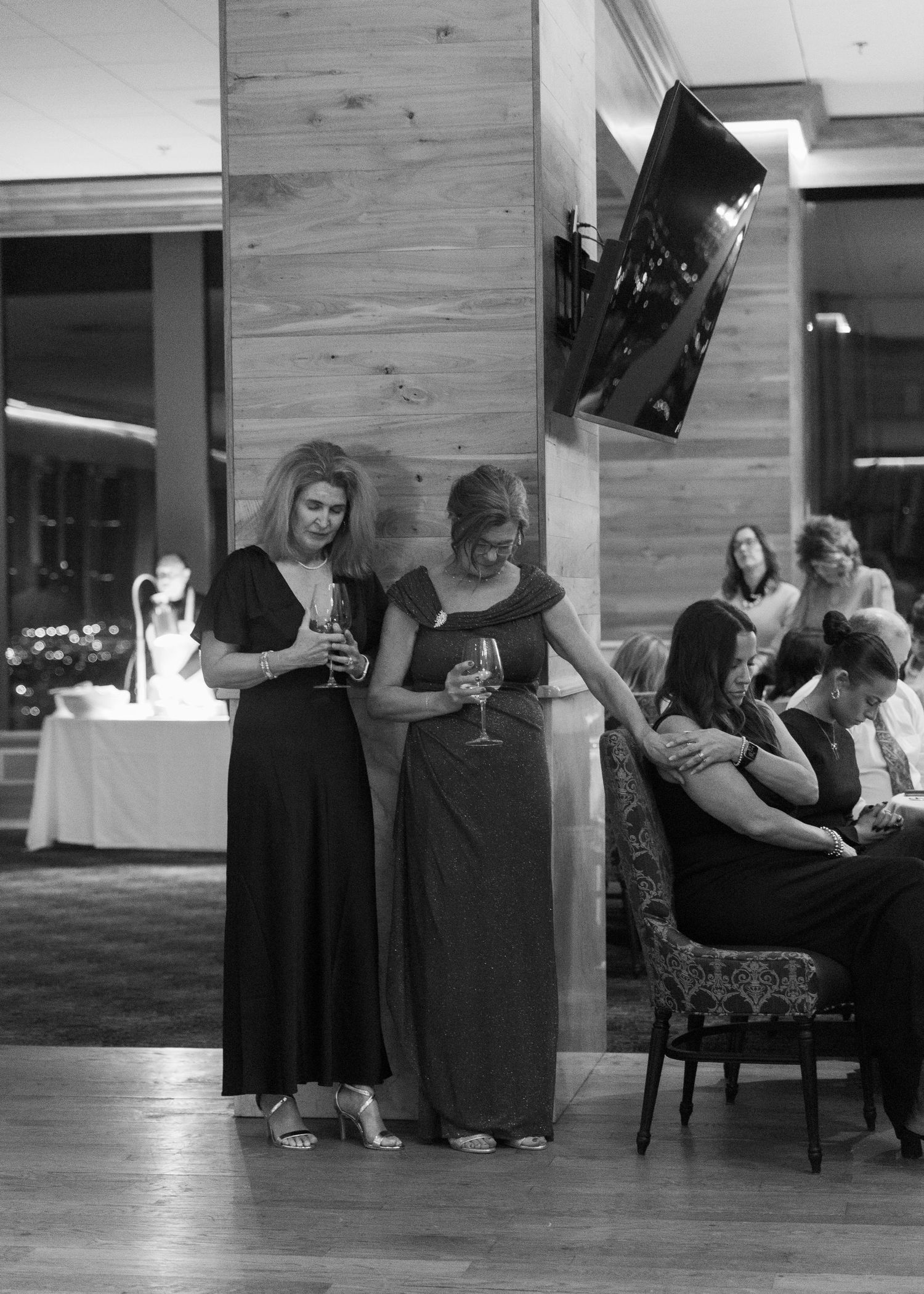 Reception venue with wooden walls and guests relaxing in formal attire.