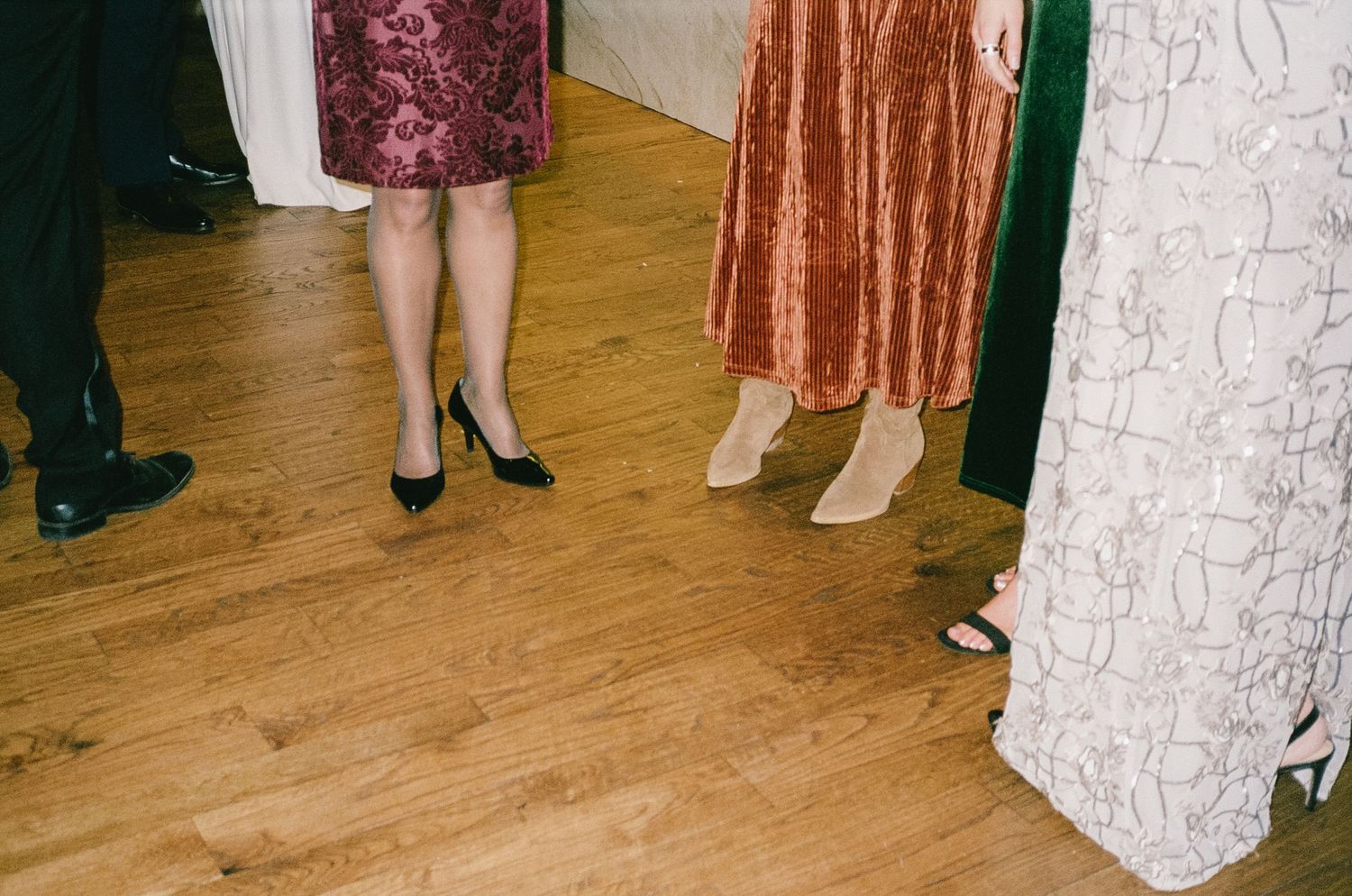 Wedding reception dance floor with guests in colorful dresses.