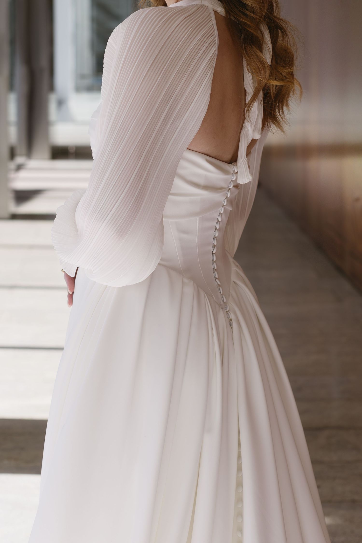 Detail shots of a wedding dress showing button closures and flowing fabric in natural light.