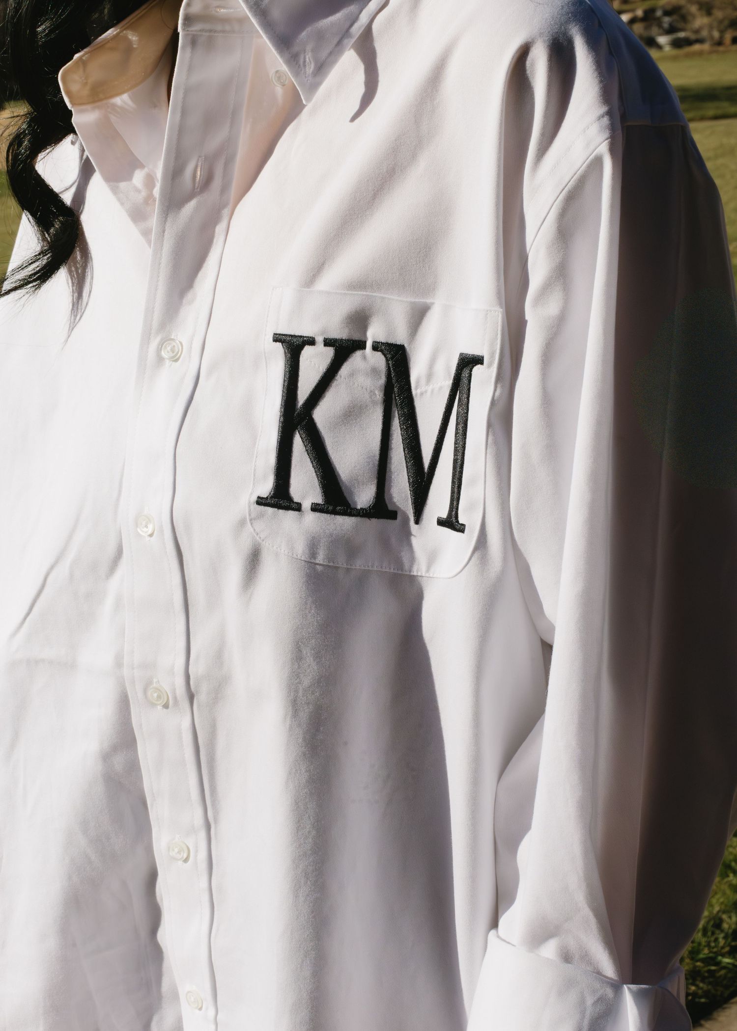 Row of white dress shirts with monogrammed details hanging in sequence.