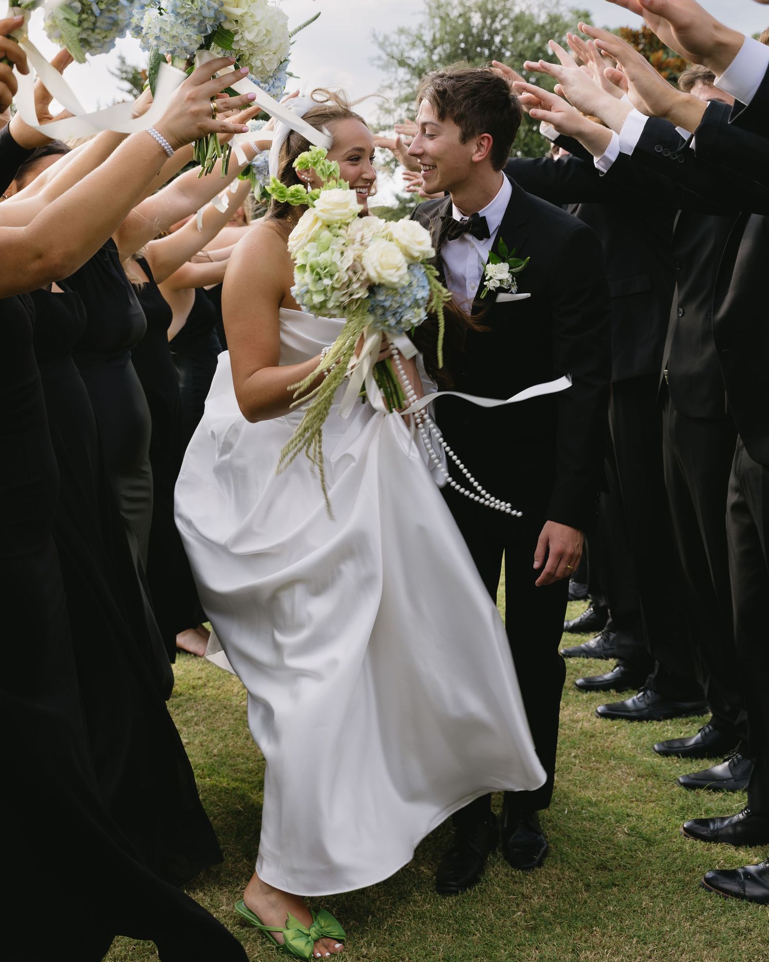 Guests throw confetti over a newlywed couple walking through a crowd after their wedding ceremony.