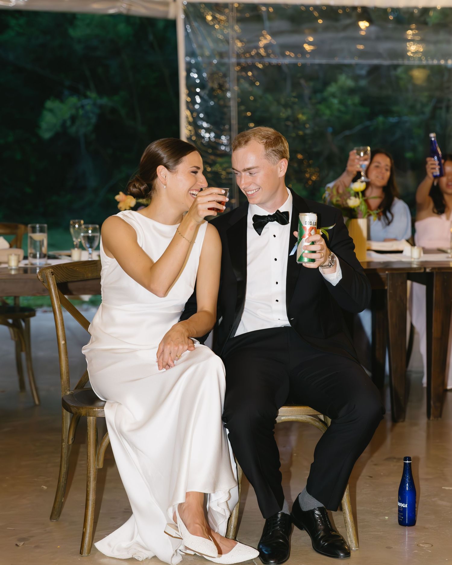 Wedding couple shares playful cake-feeding moments at reception under twinkling lights.