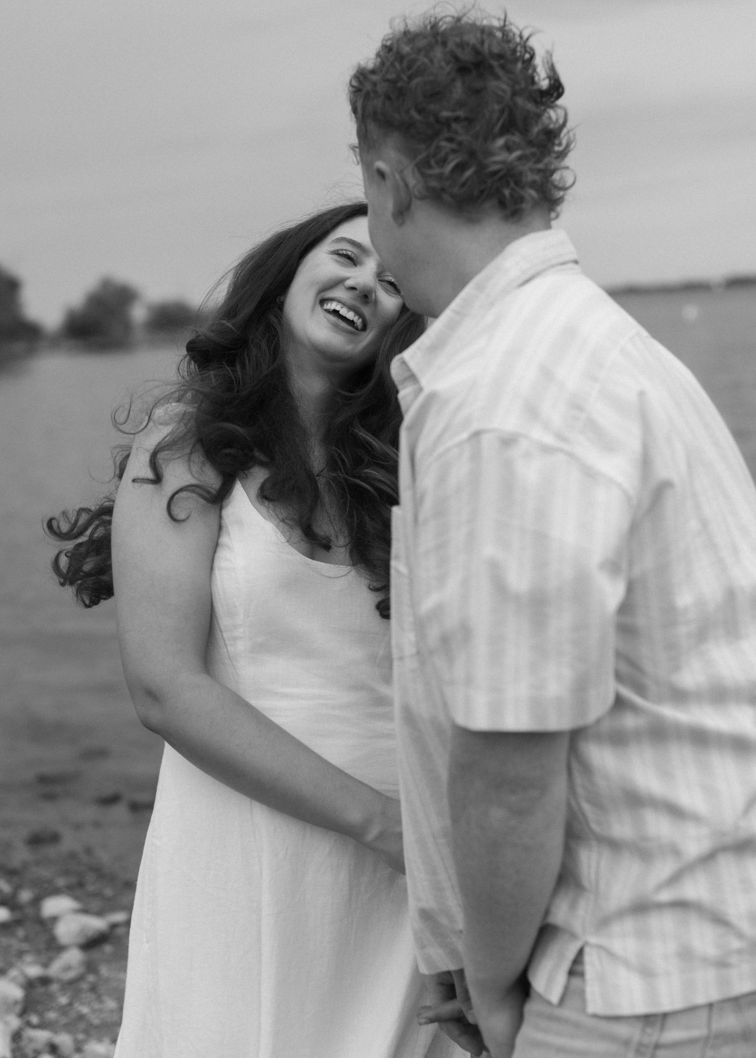 Black and white sequence showing a couple laughing and embracing by the water.