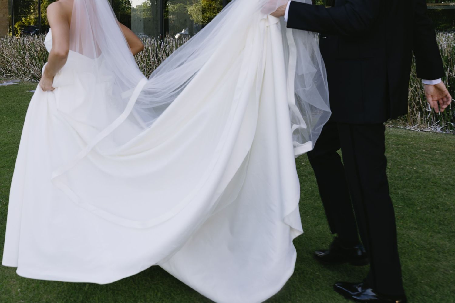 Wedding party in formal attire gathering on outdoor lawn.