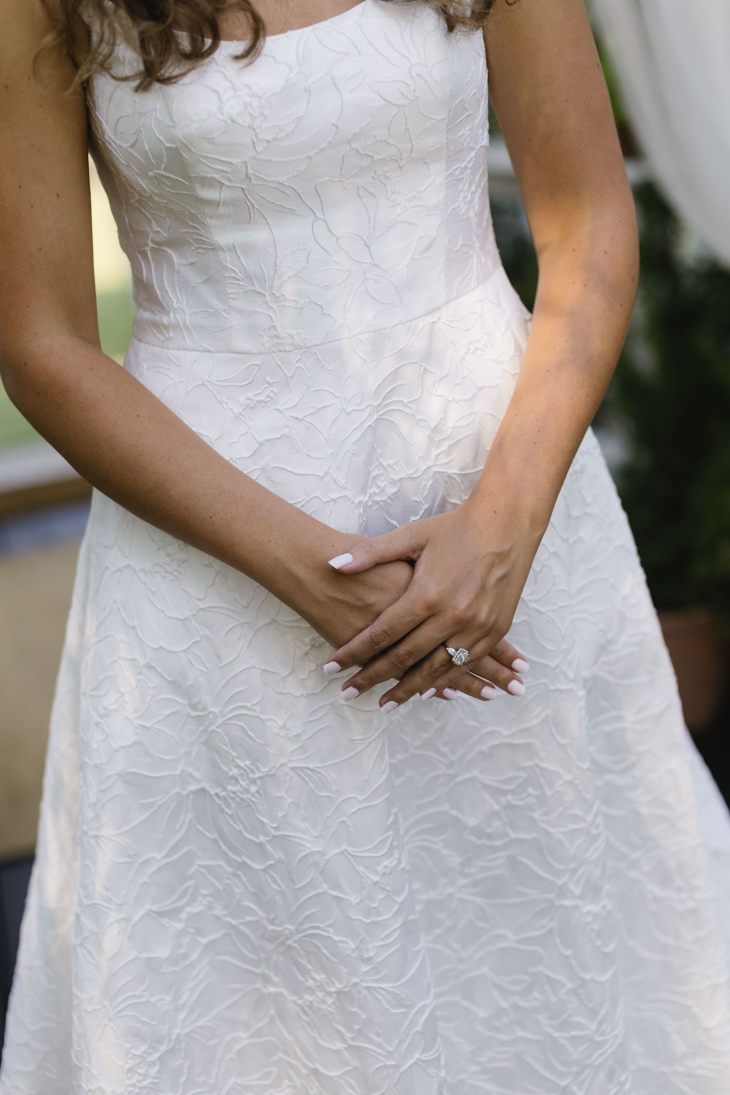 Close up details of a white lace wedding dress bodice with delicate floral patterns.