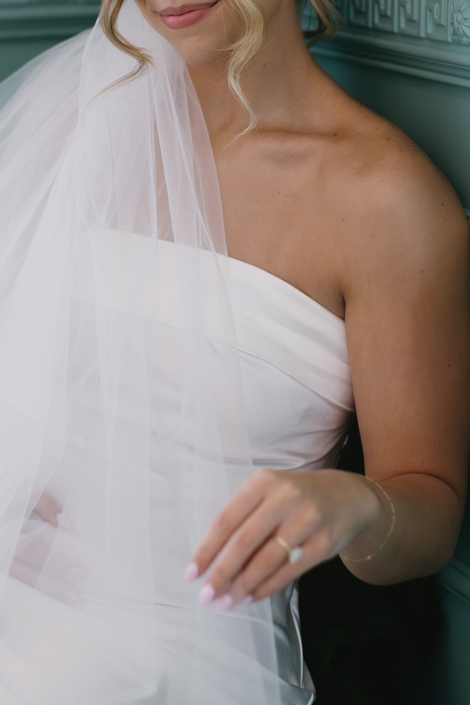 A series of close-up shots showing details of a white wedding dress with delicate tulle overlay and one-shoulder design.
