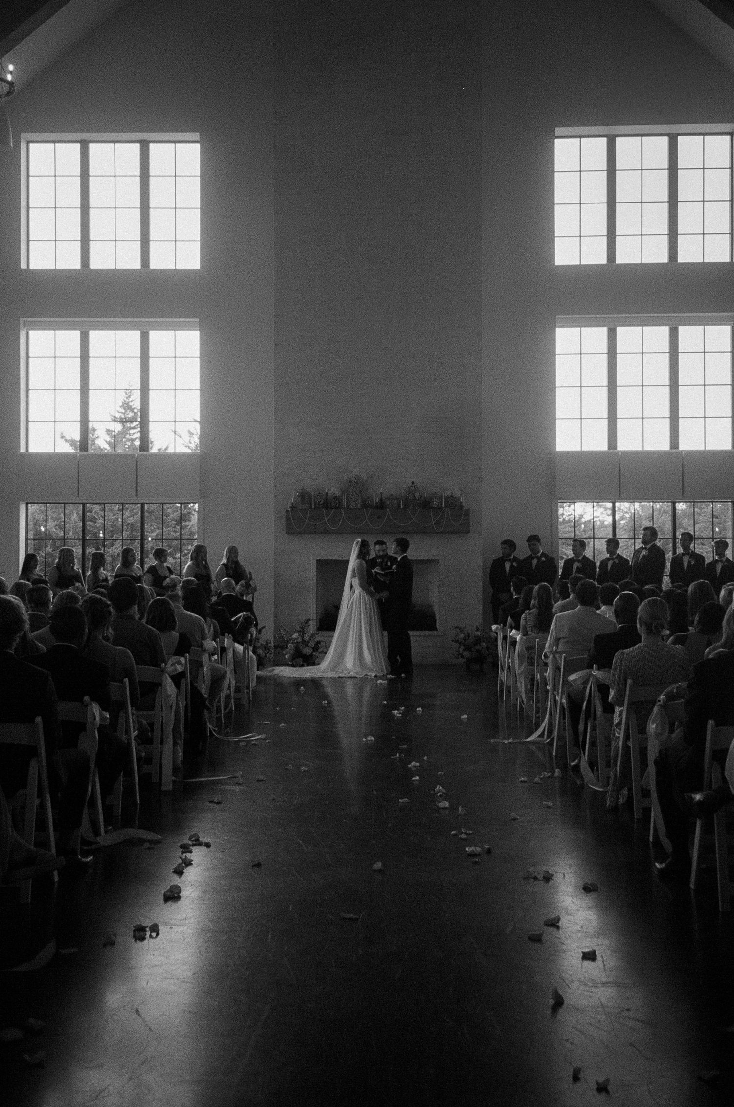 Black and white photograph of a wedding ceremony space with rows of chairs and natural light.