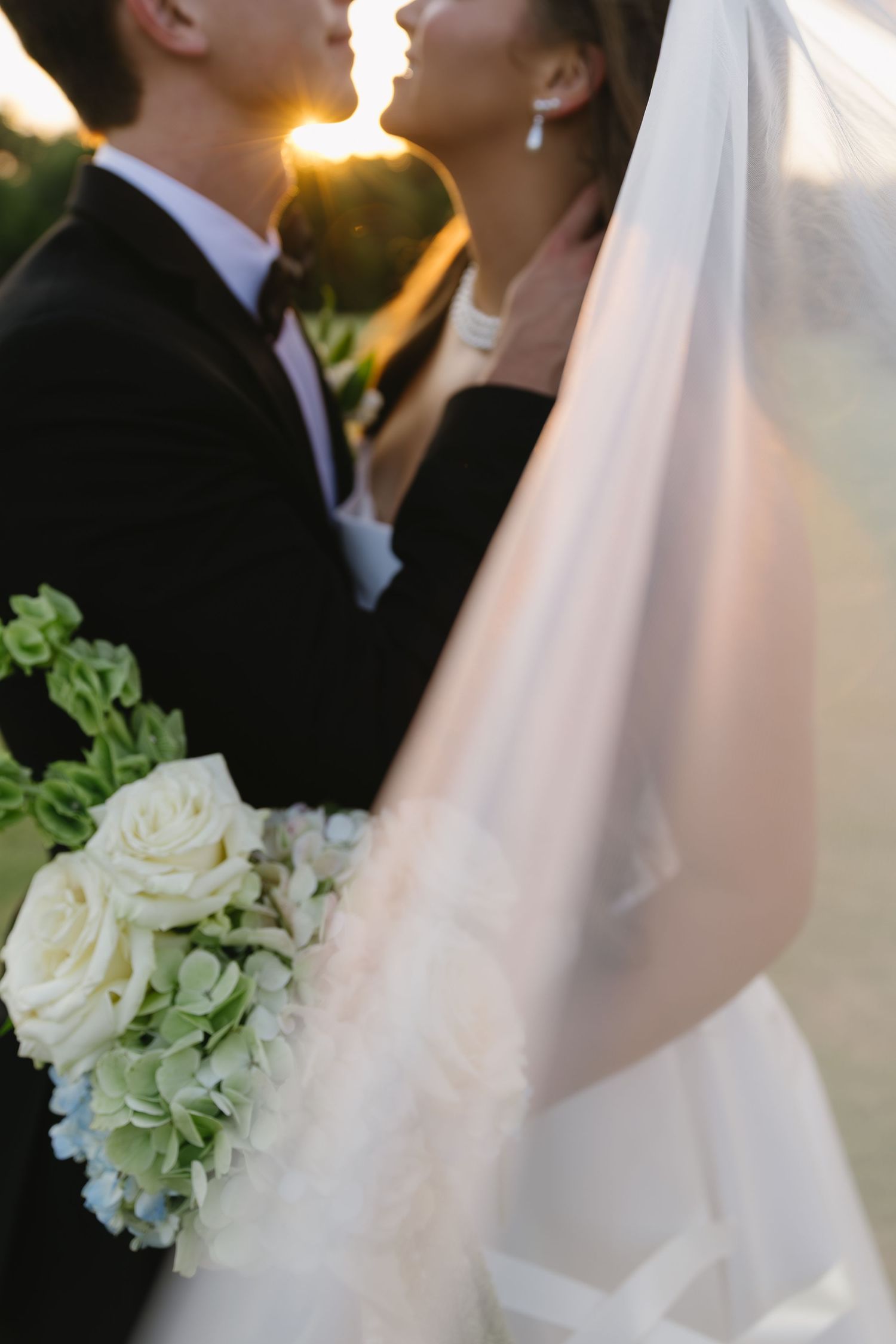 Elegant white and green floral bouquet against wedding dress at sunset.