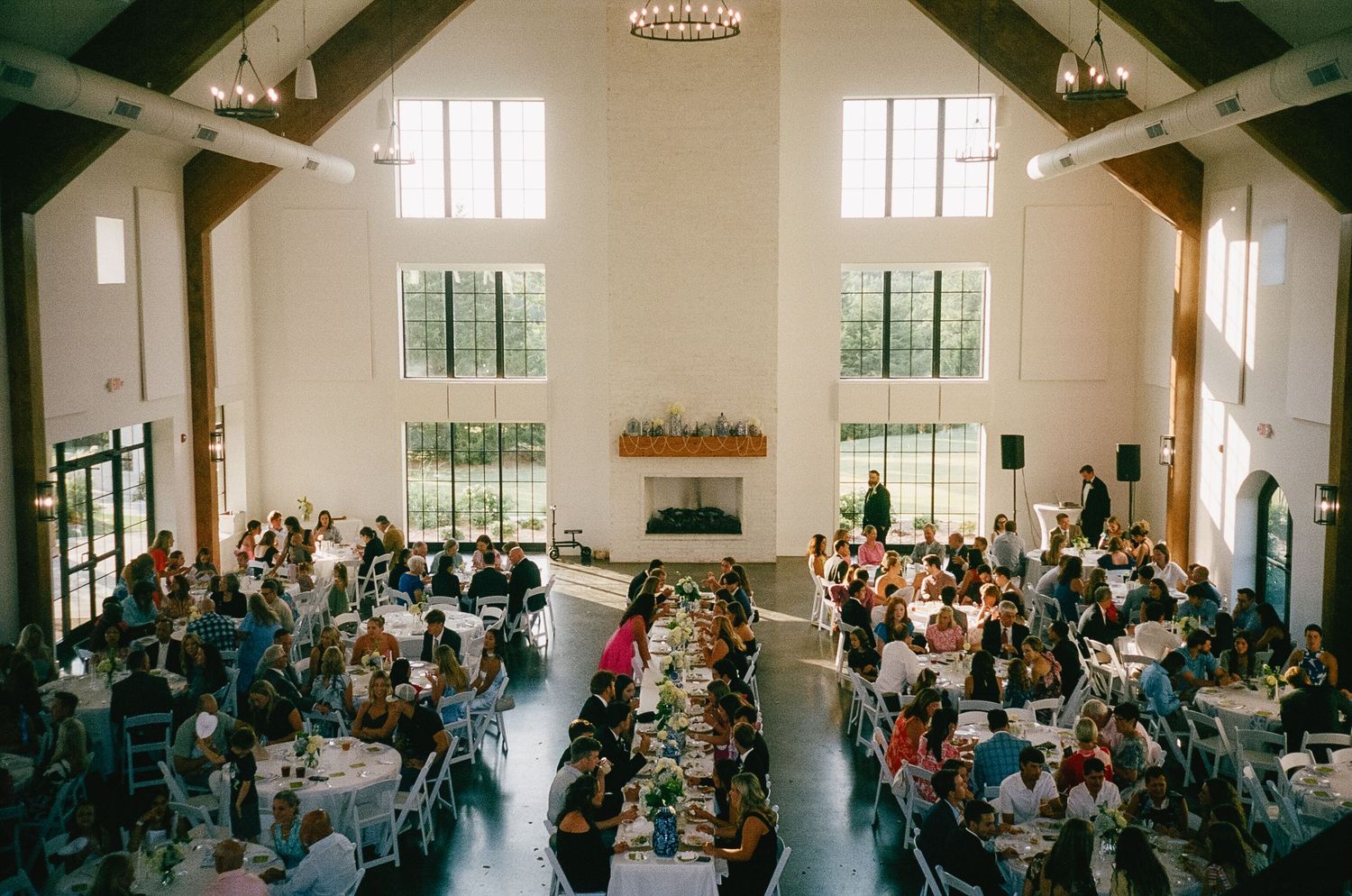 Wide view of wedding ceremony in spacious chapel with high ceilings and natural light.