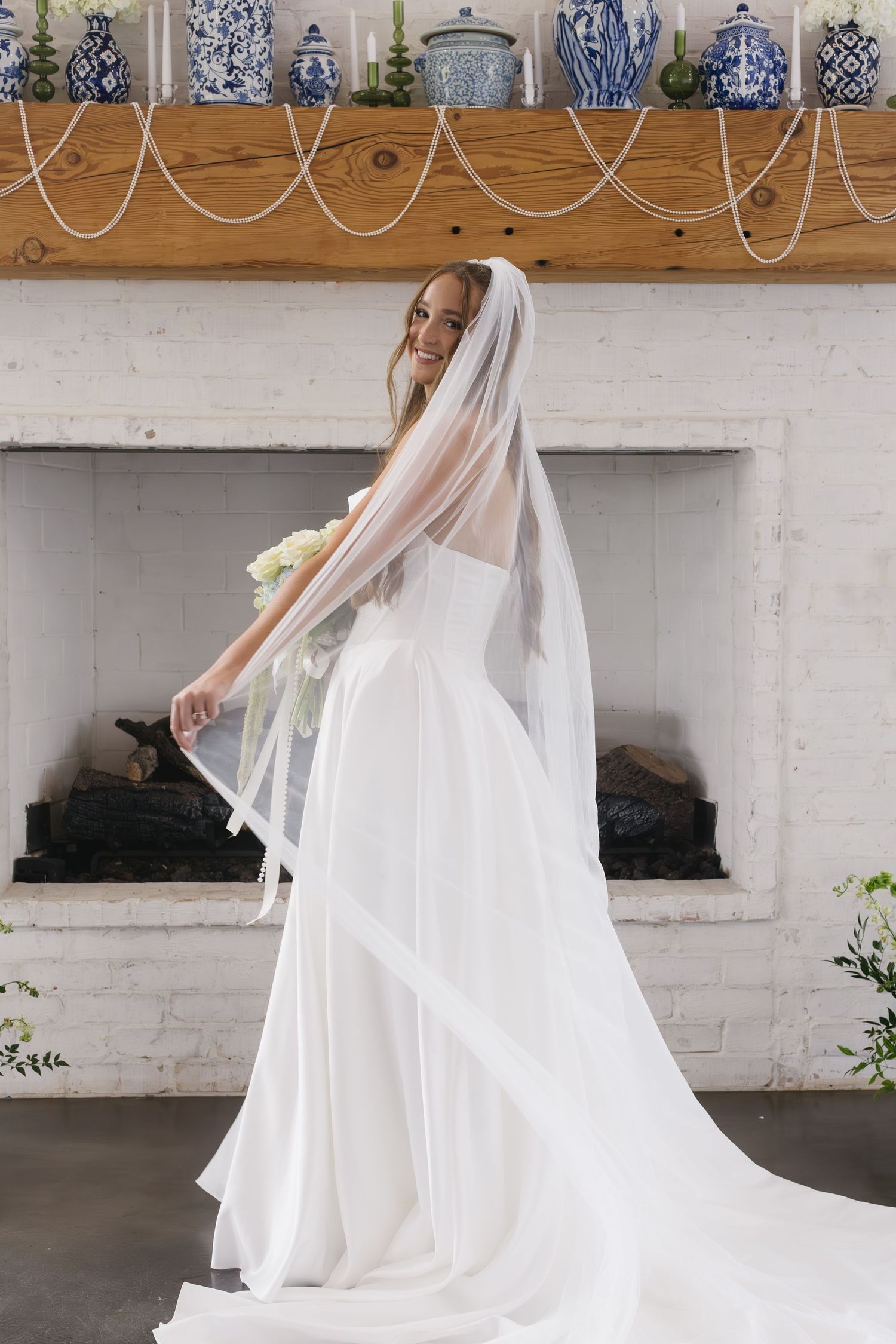 Elegant wedding dress and veil displayed against a wall with blue and white decor.