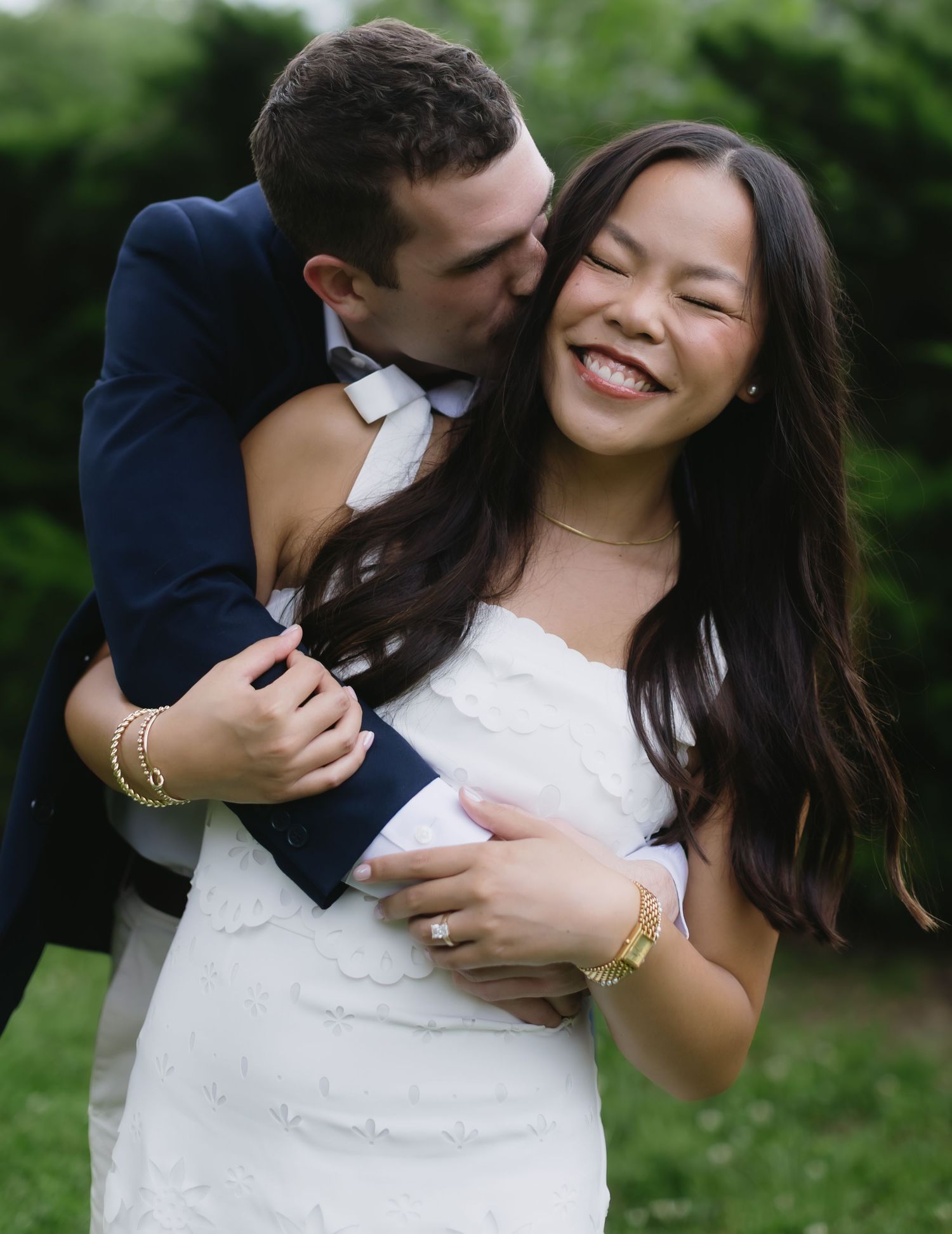Romantic photo series captures joyful couple laying on grass and sharing tender moment in white dress and navy suit.