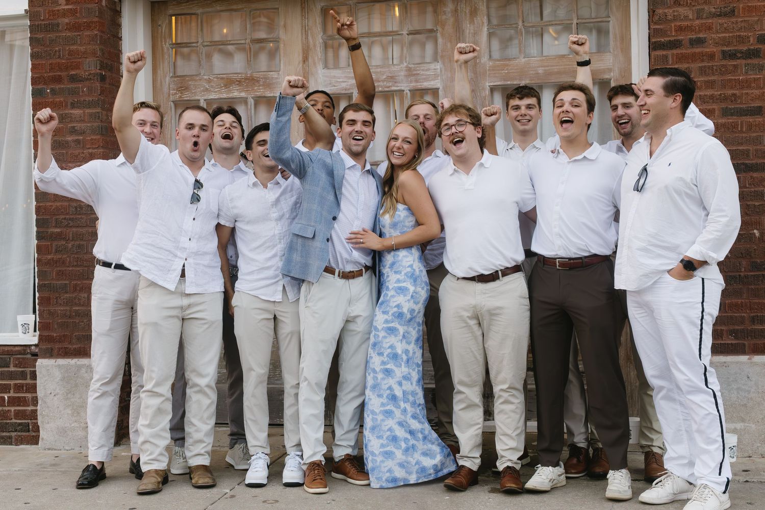 Large group photo of wedding party members in coordinated blue and white attire.