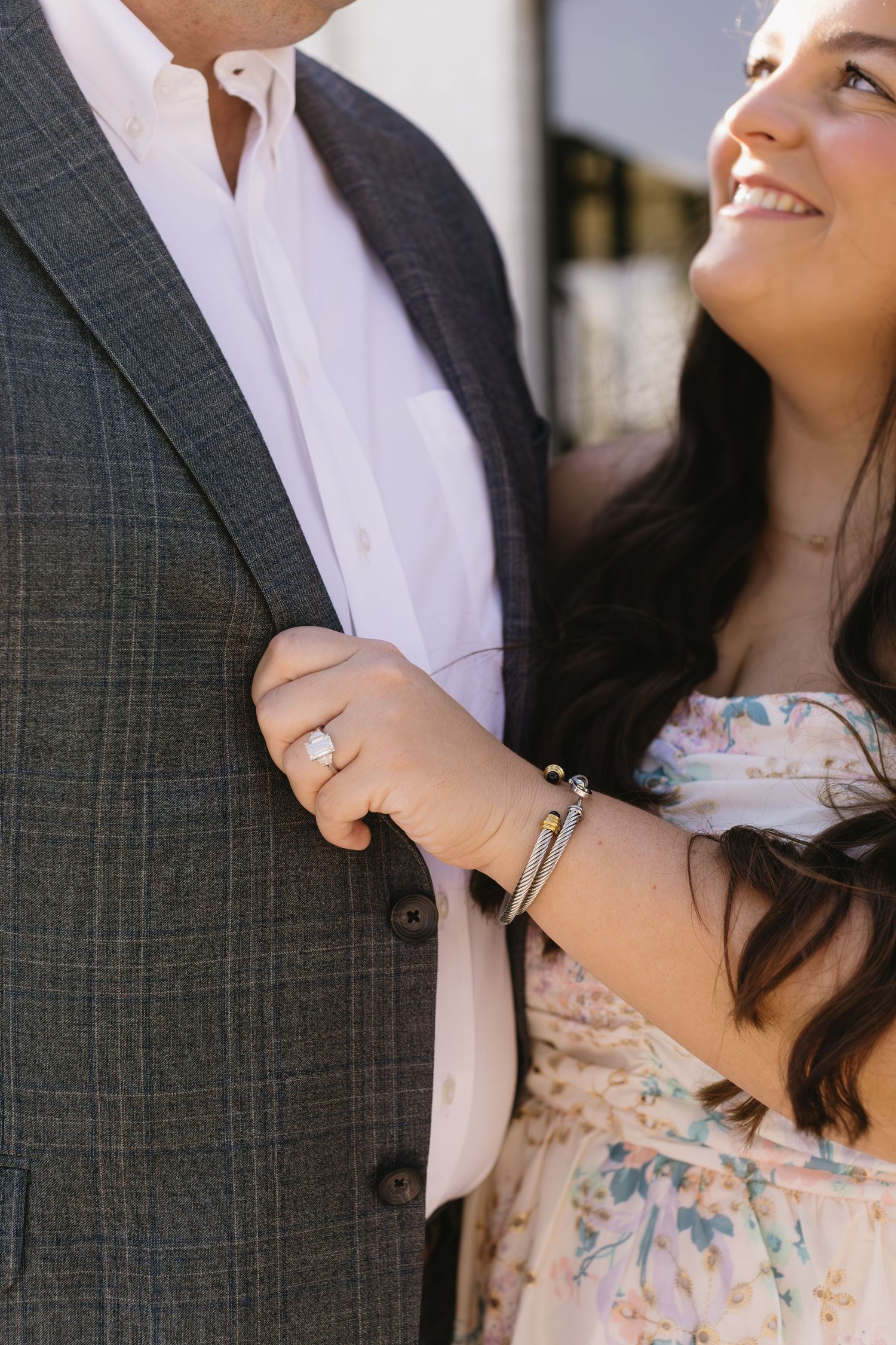 Close up details of a couple in a floral dress and gray suit showing affectionate gestures.