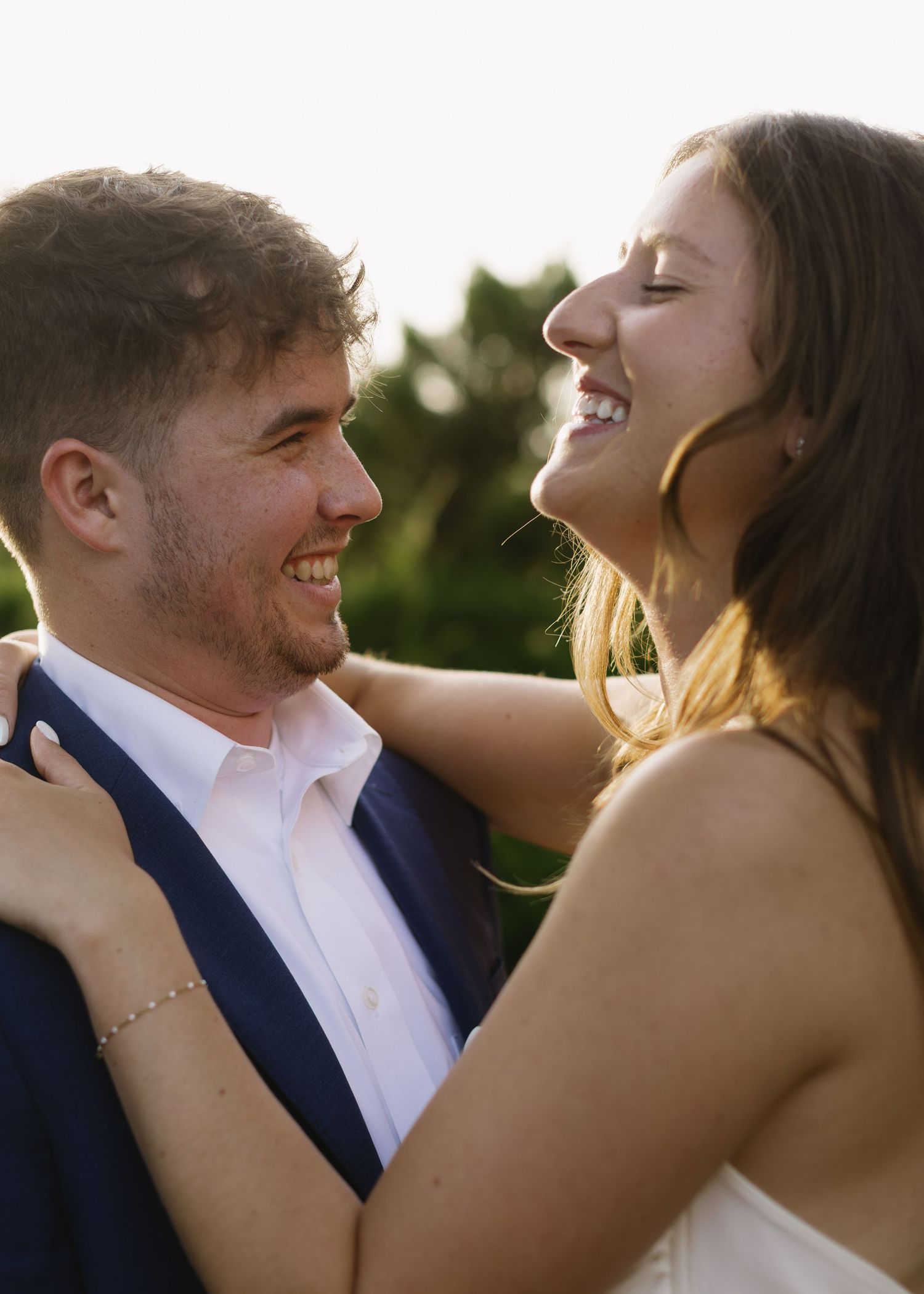 A loving couple enjoying a tender moment together in romantic backlit sunlight against a sunset backdrop.
