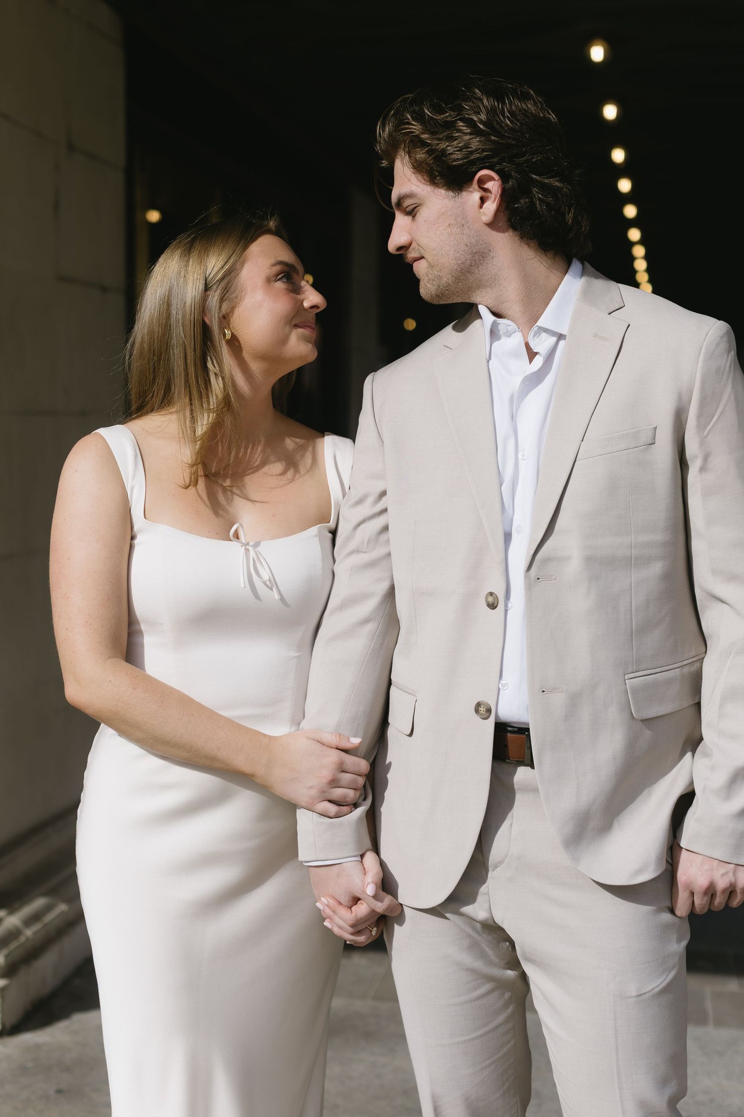 A couple in matching light colors sharing romantic moments in a dimly lit setting.