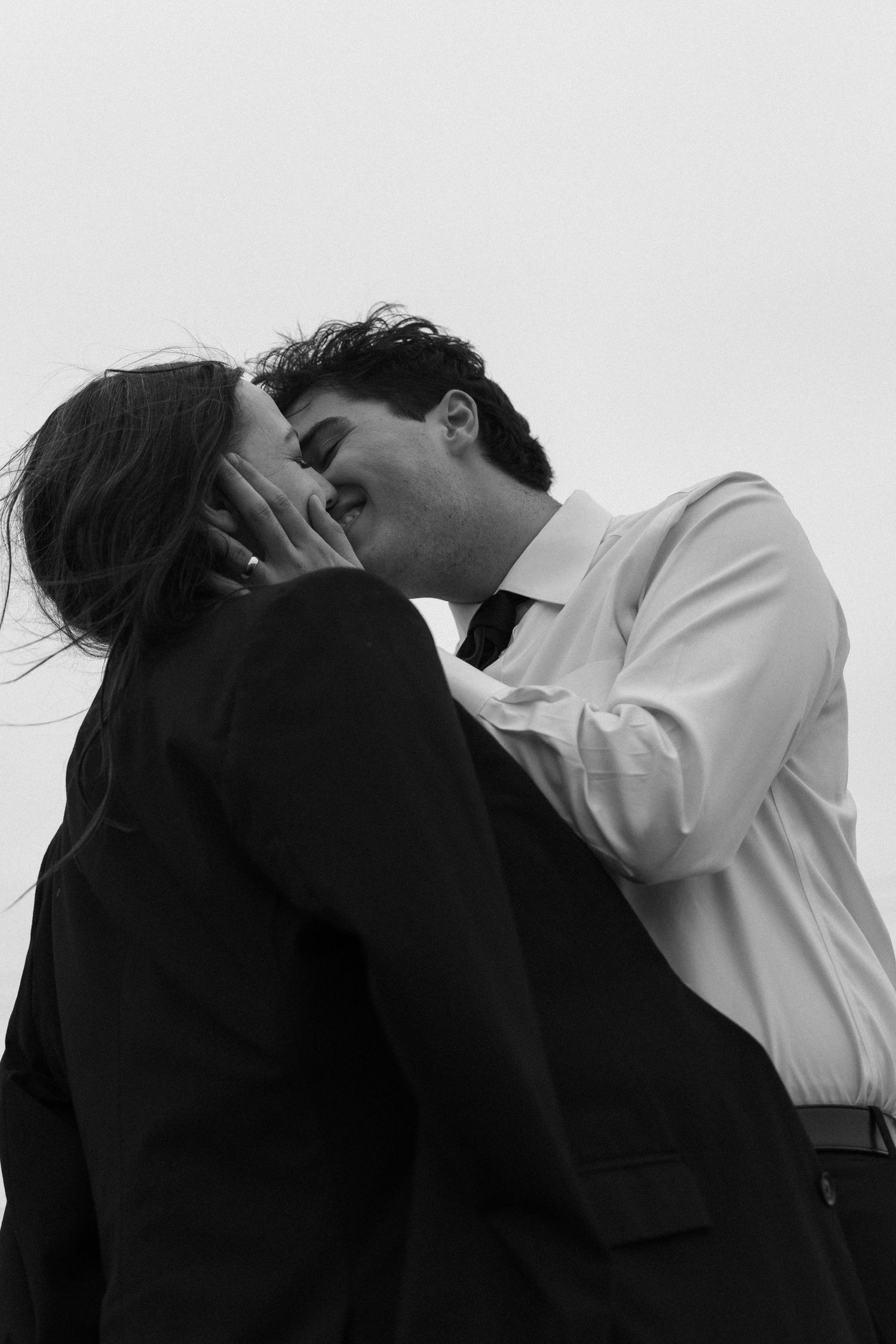Silhouetted couple sharing an intimate moment against white background in artistic black and white.