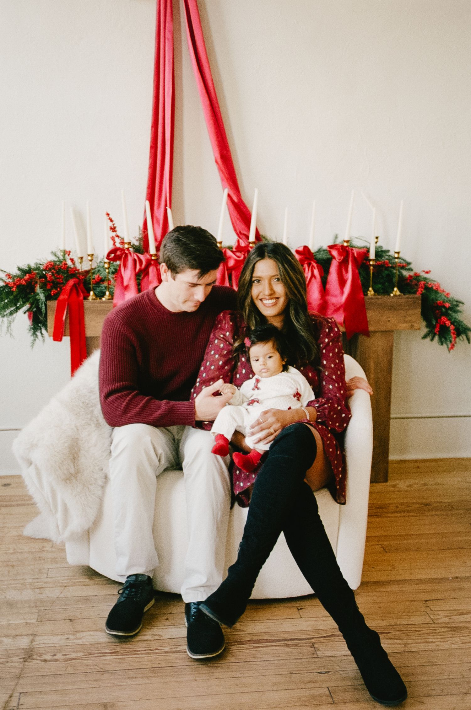 Casual holiday photos with red fabric draping and festive greenery decorations.