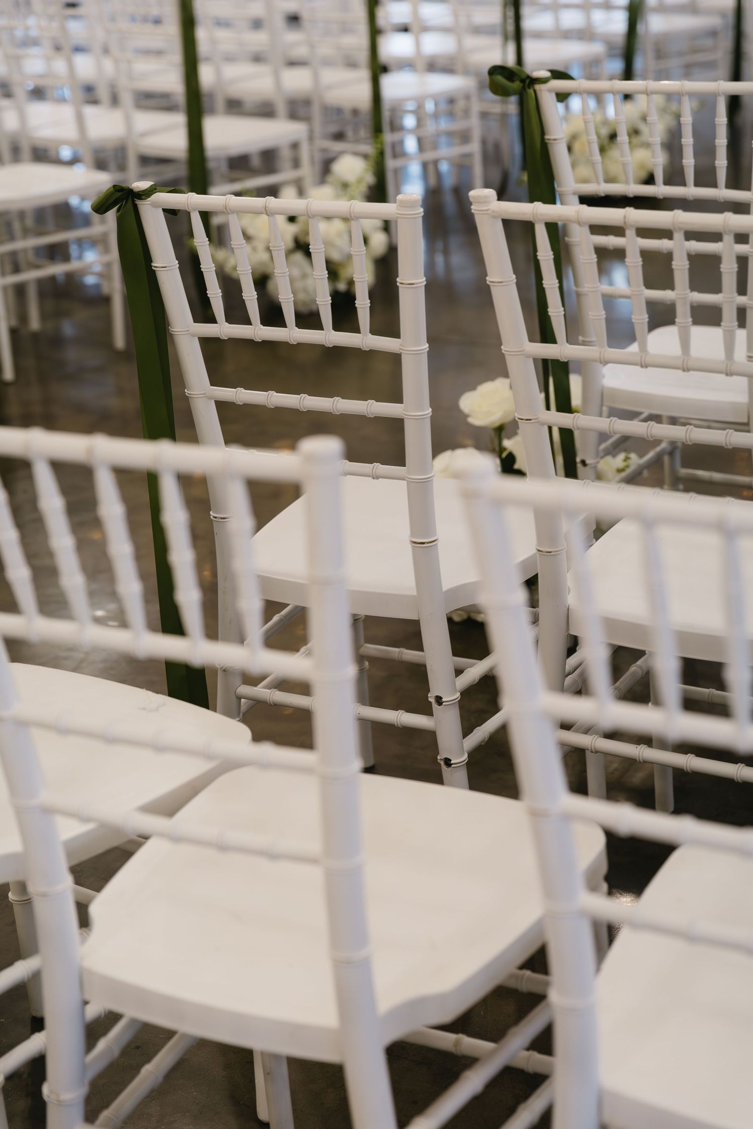 Row of white wooden chairs arranged for a wedding ceremony.