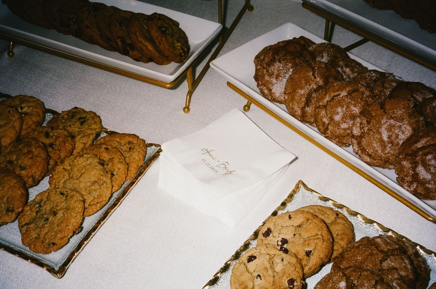 Array of freshly baked chocolate chip cookies displayed on white baking sheets.