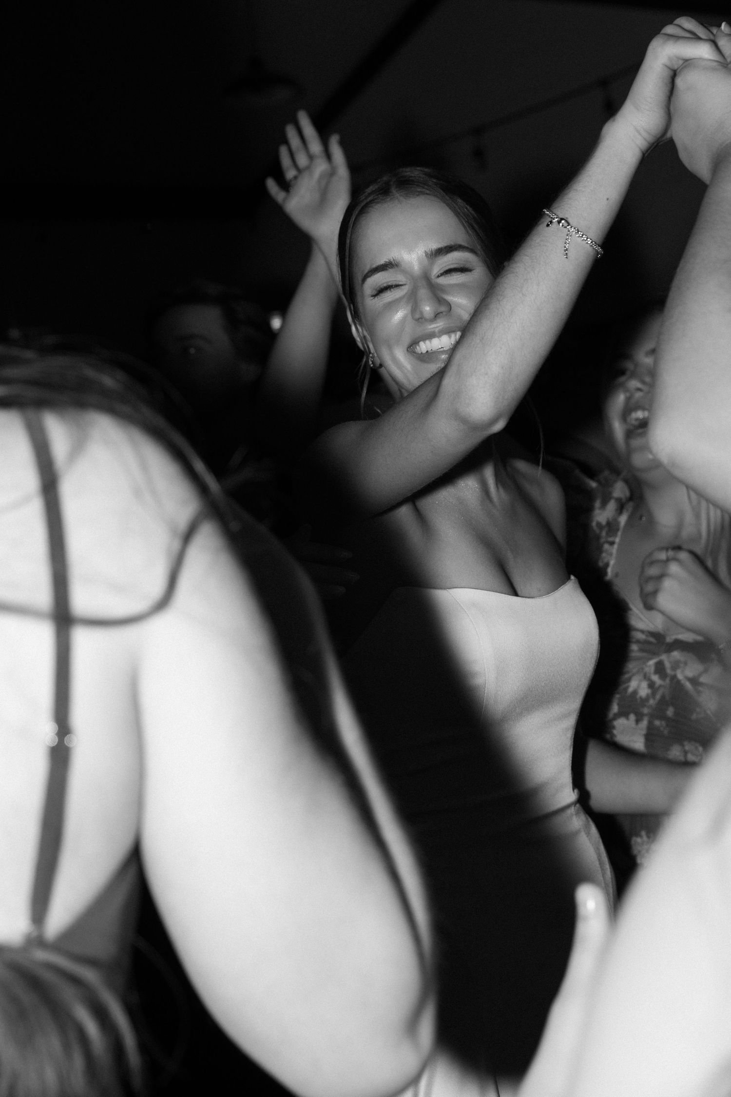 Black and white photo of wedding celebration with dancing and raised arms.