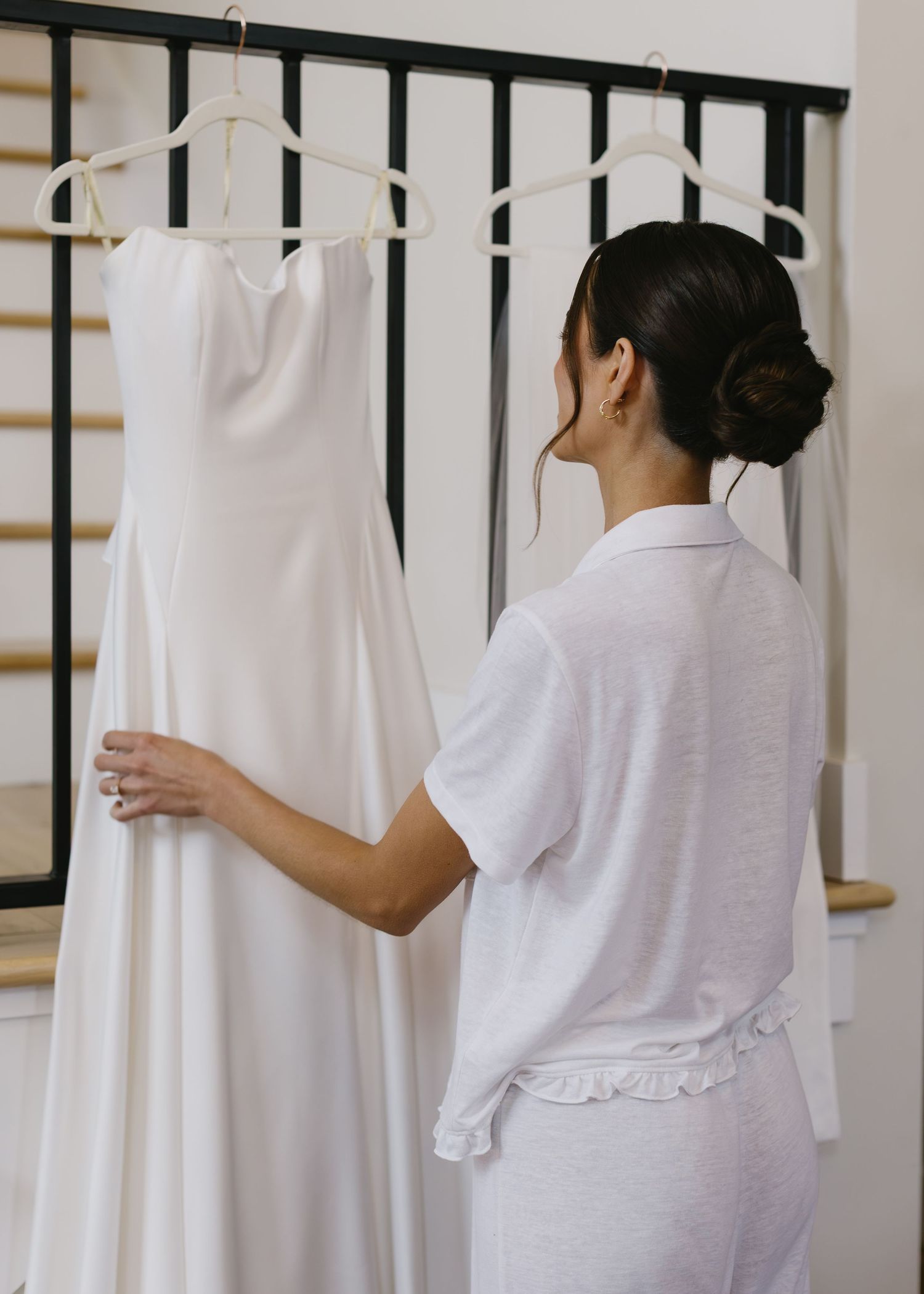 White wedding dresses hanging on display against black and gold accented wall.