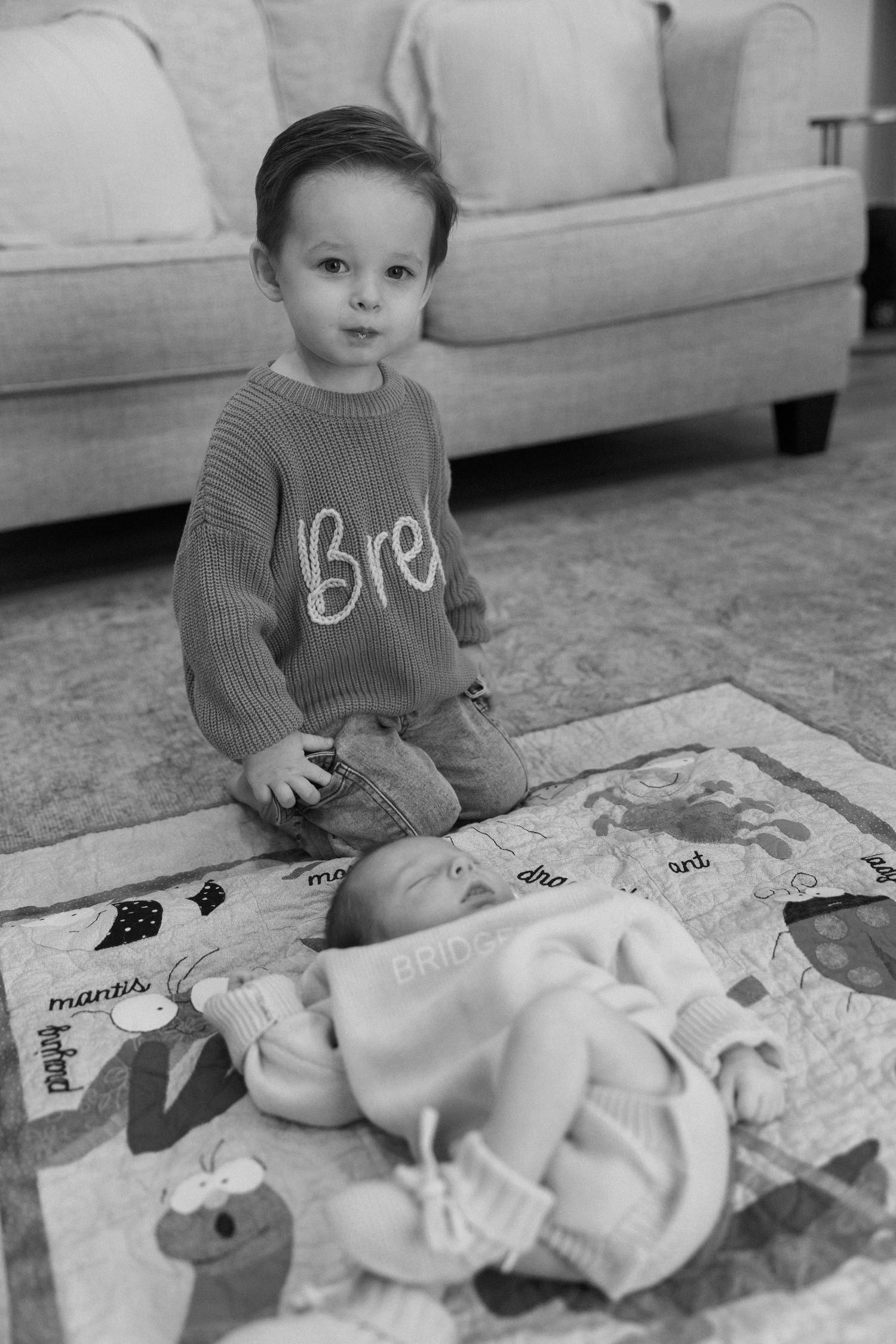 A sequence of black and white photos showing a baby sitting on a blanket on the floor.