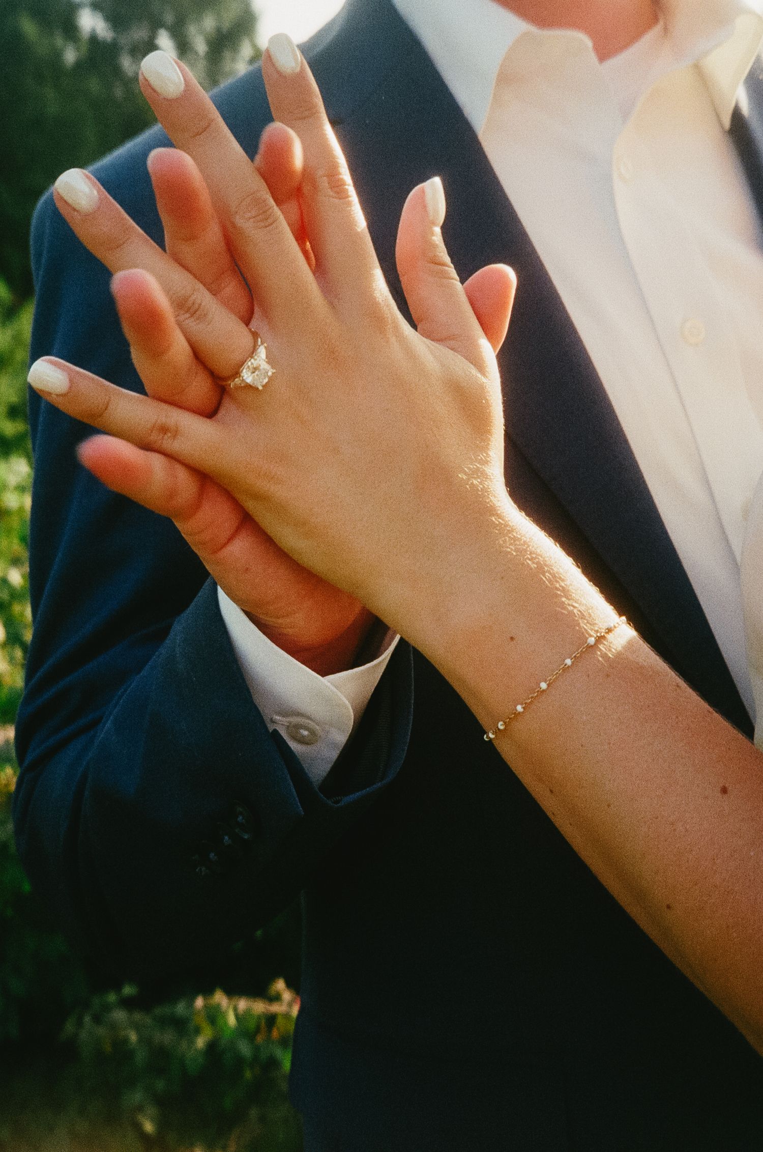 Close-up shots of hands displaying engagement rings and jewelry in natural outdoor lighting.