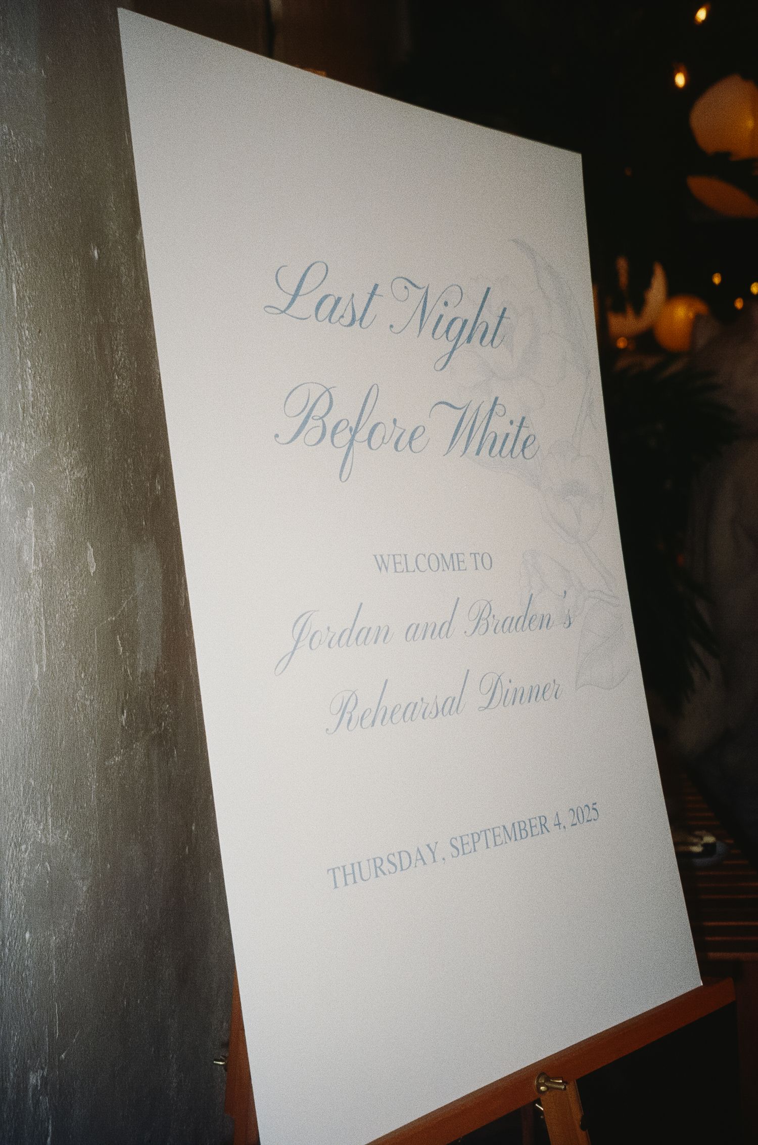 Wedding signage with calligraphy text displayed on white boards against a dark background.