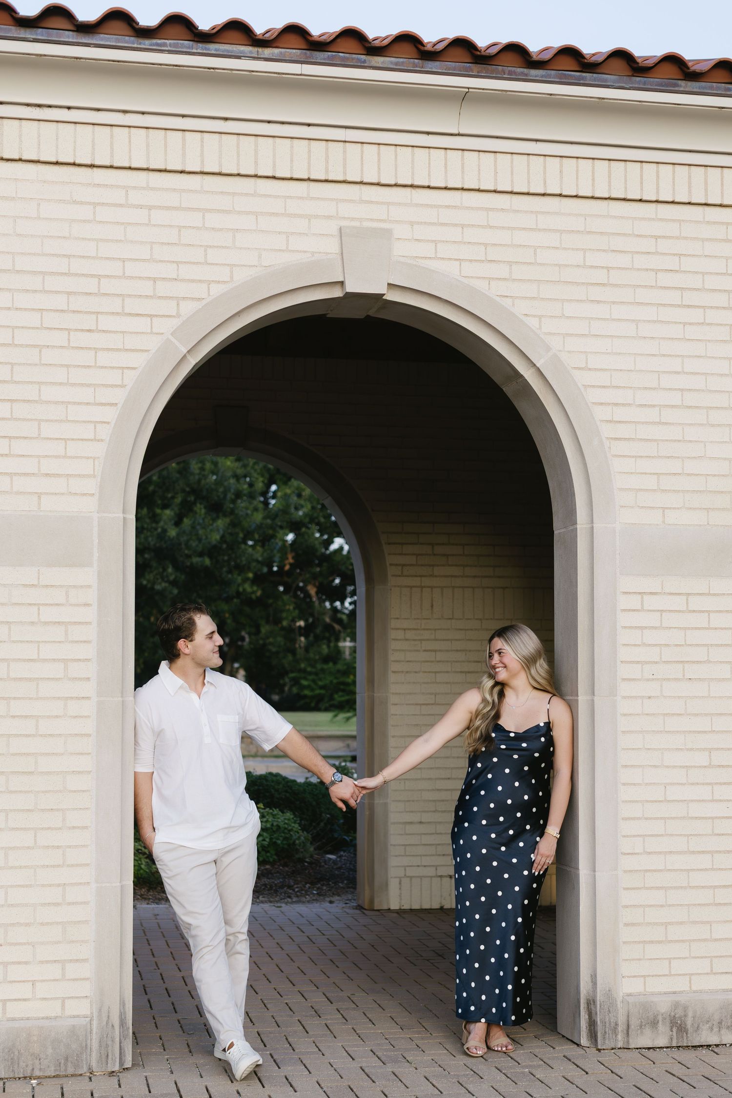 Playful dance sequence under white archways showcases polka dots and all-white outfits.