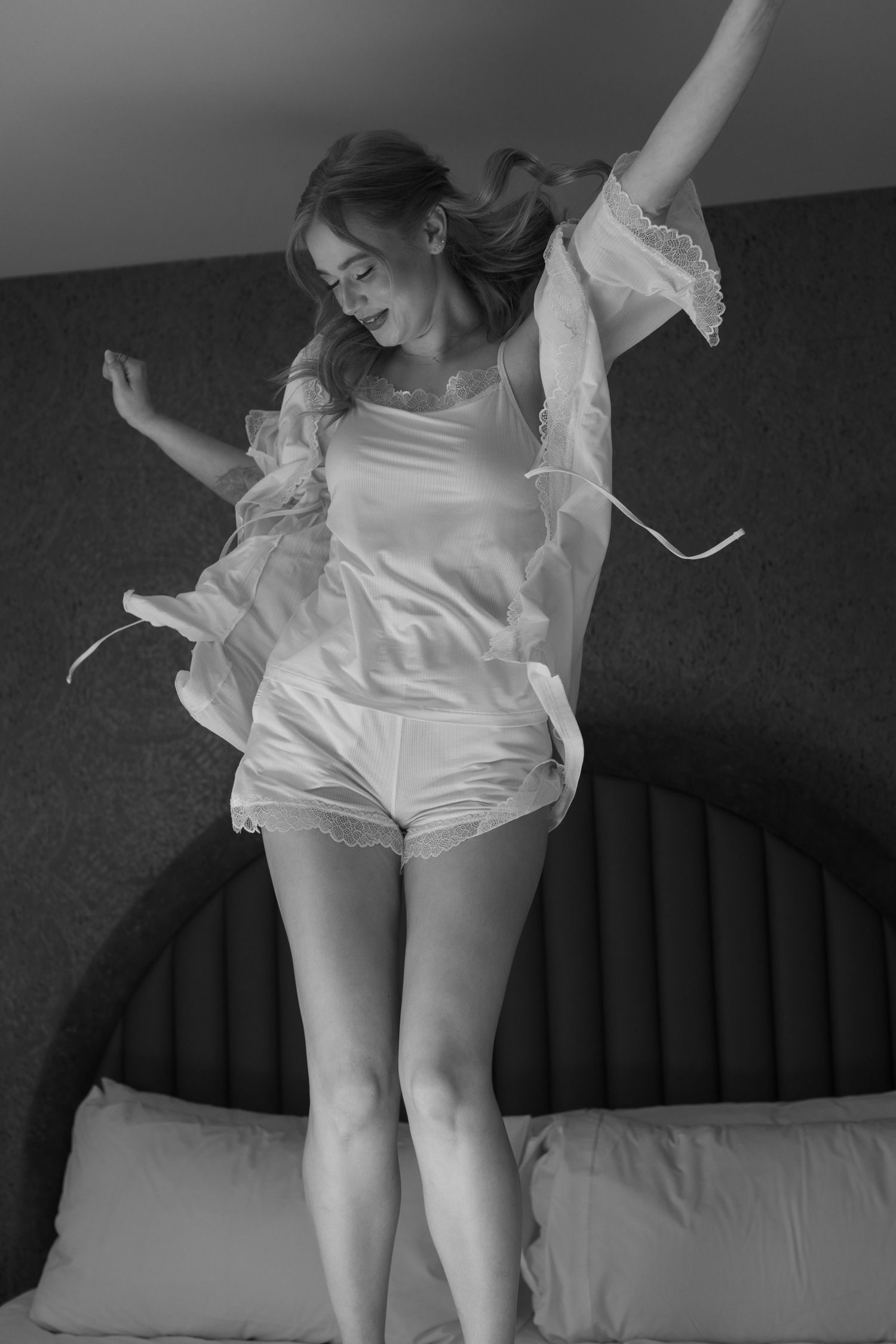 Artistic black and white photo of flowing white fabric in motion on a bed.