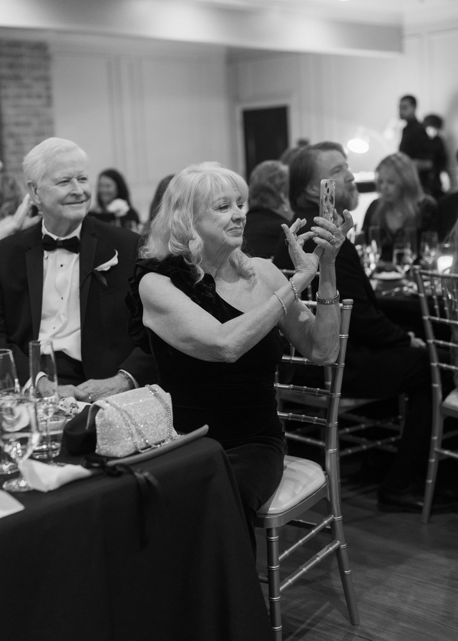 Black and white photograph of guests enjoying a formal celebration at an elegant reception.