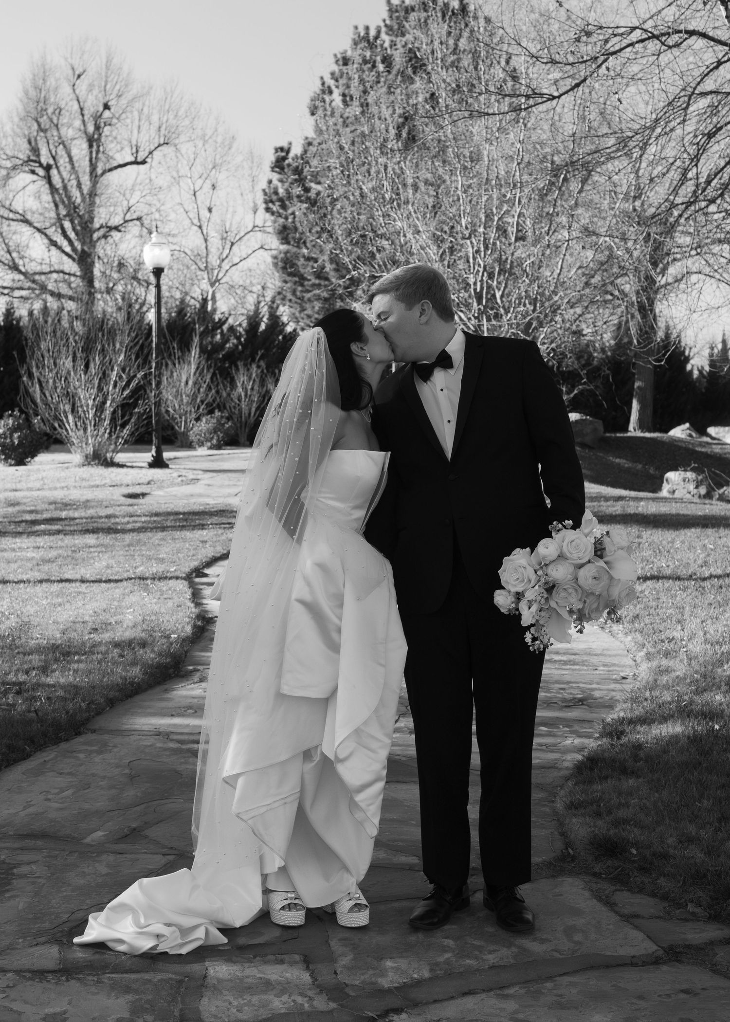 Black and white photos of a couple posing together on their wedding day in an outdoor setting.